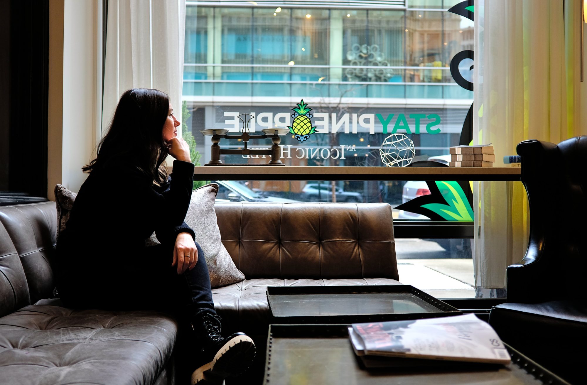 Alyssa sits and looks out the window of the lobby at Staypineapple