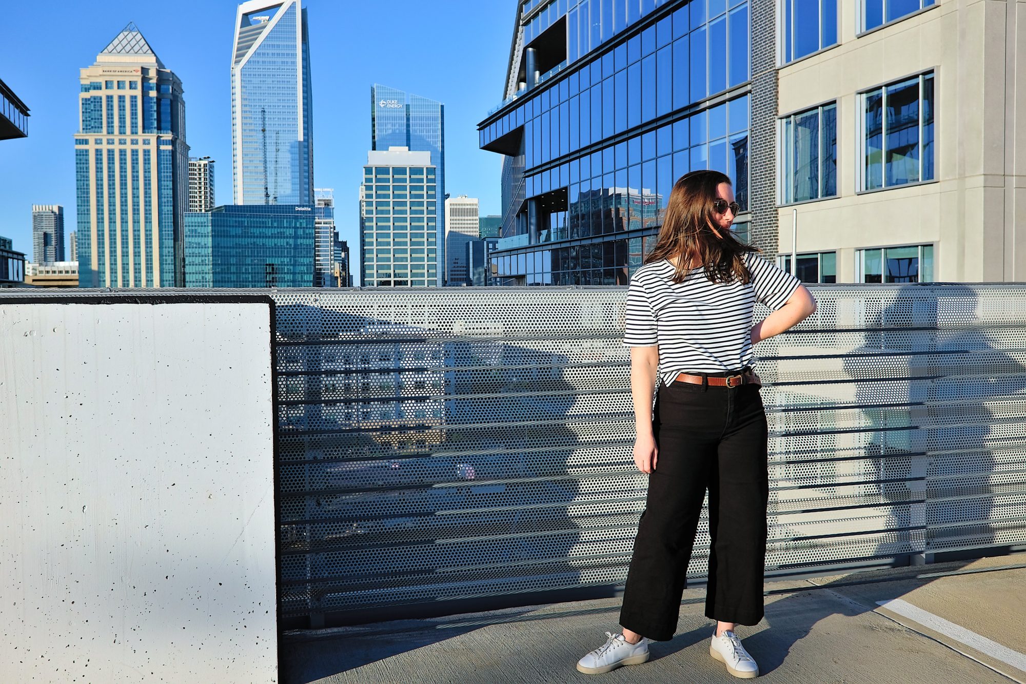 Alyssa stands on a parking deck rooftop with the Charlotte skyline in the background