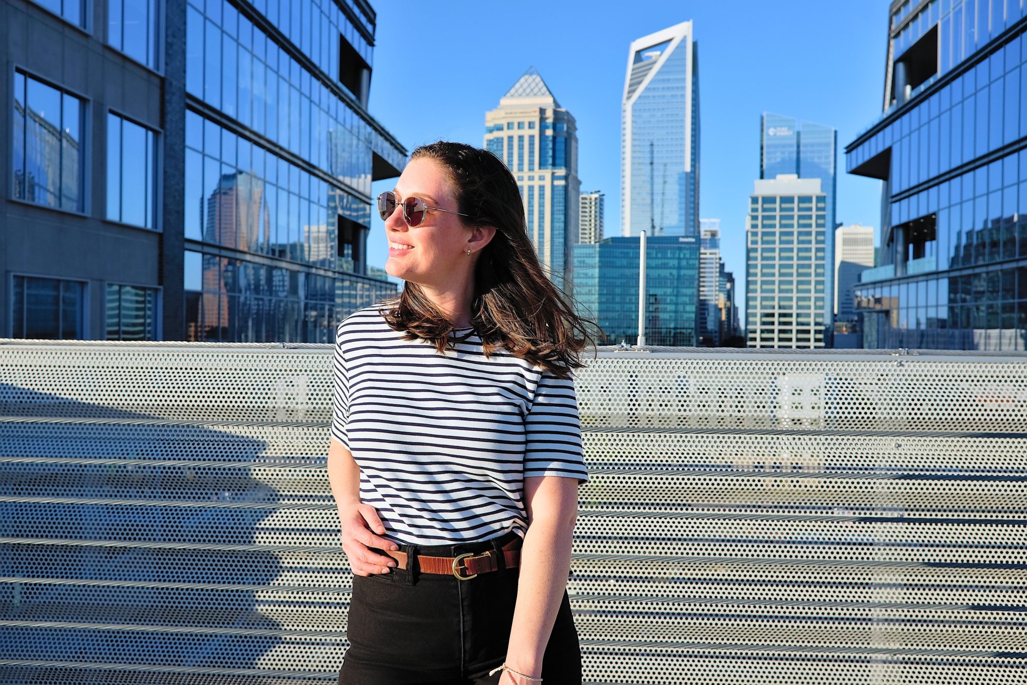 Alyssa wears the tee from ABLE and stands in front of the Charlotte skyline