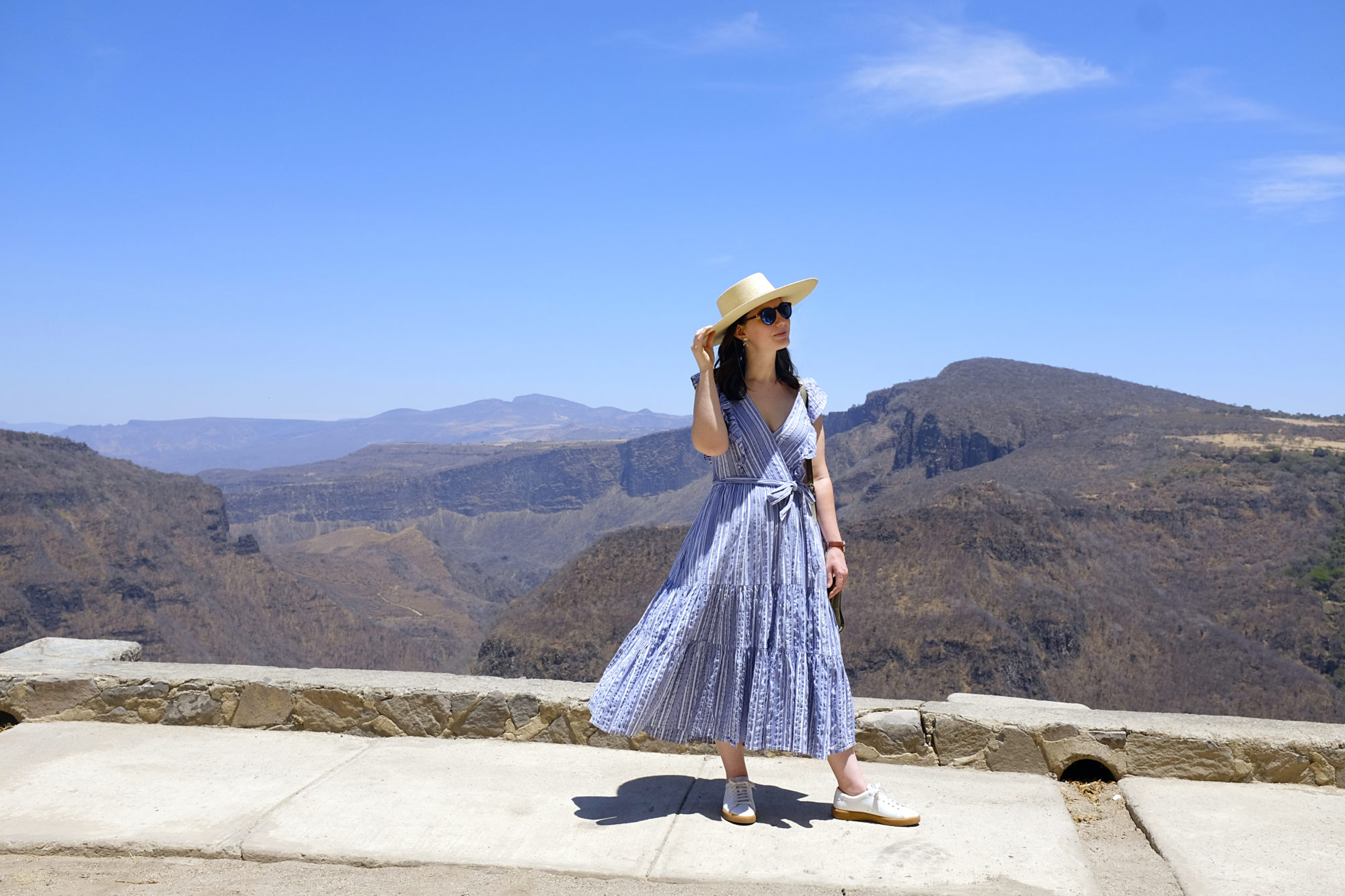 Alyssa stands in front of a canyon in a blue dress