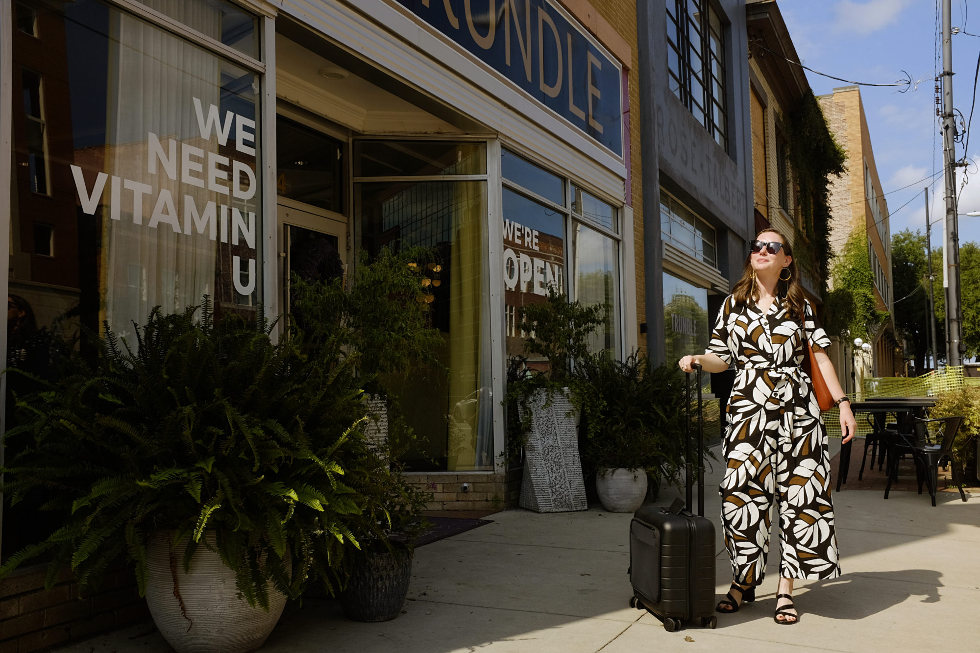 Alyssa stands outside of Hotel Trundle with a suitcase