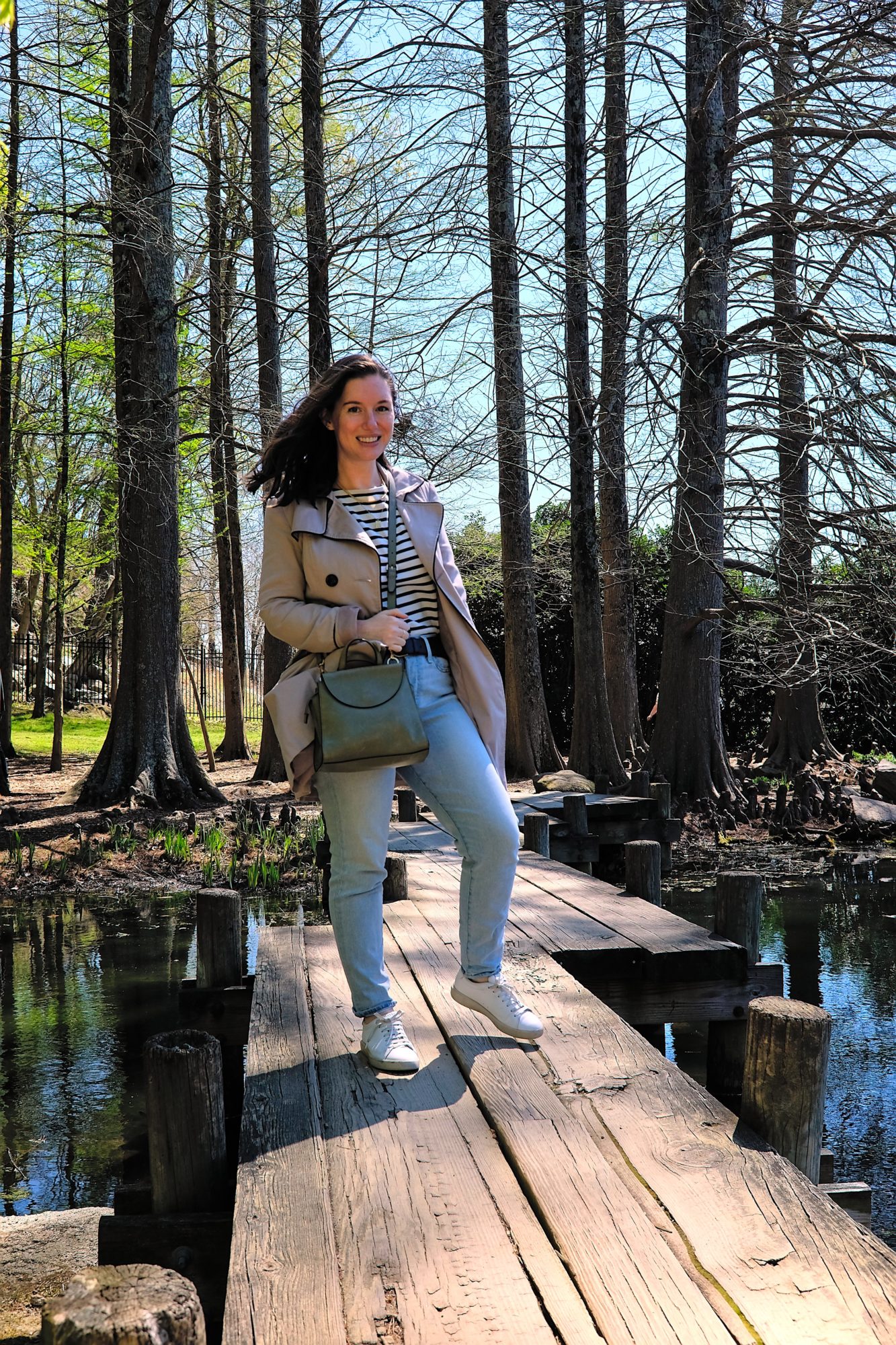 Alyssa wears a Breton top with jeans and a trench
