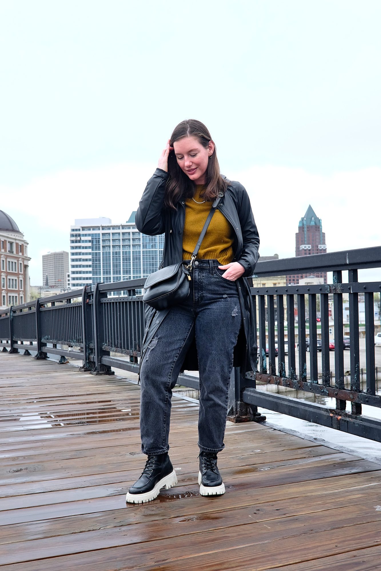 Alyssa wears a sweater, jeans, rain coat, and boots in Milwaukee