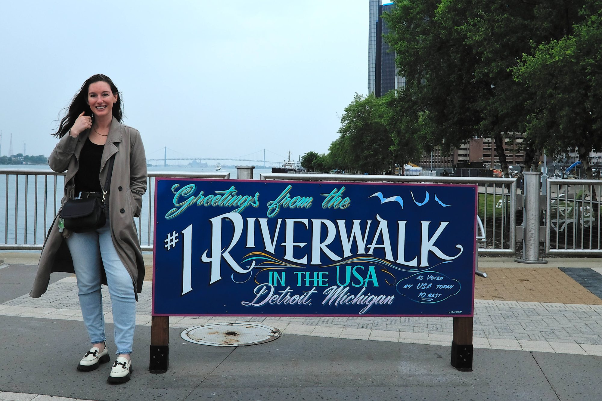 Alyssa stands in front of a Detroit Riverwalk Sign