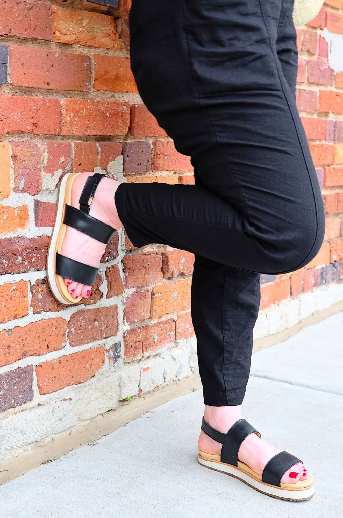 Alyssa leans against a wall while wearing the Flatform Sandals