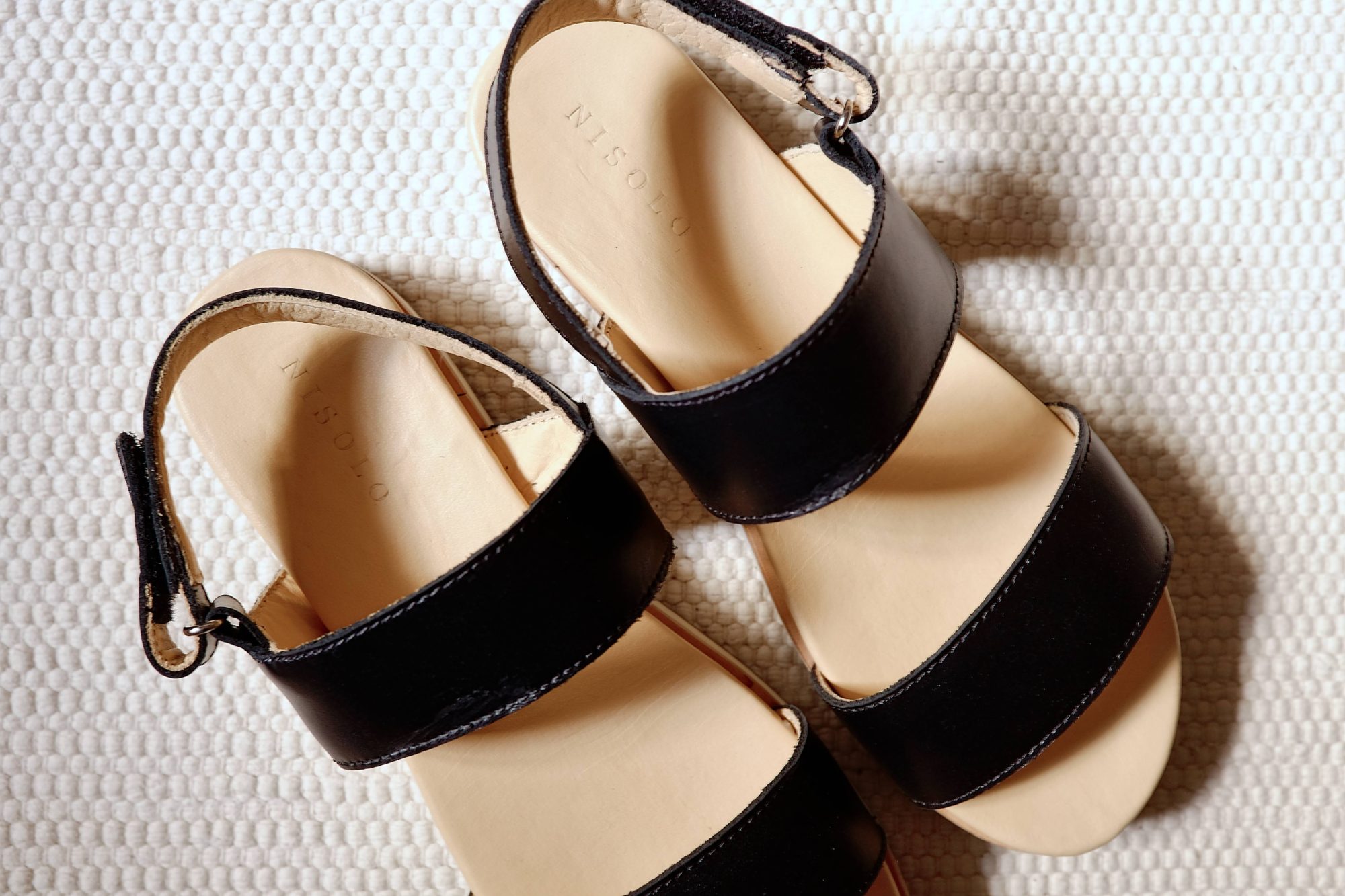 A pair of Nisolo sandals on a white carpet