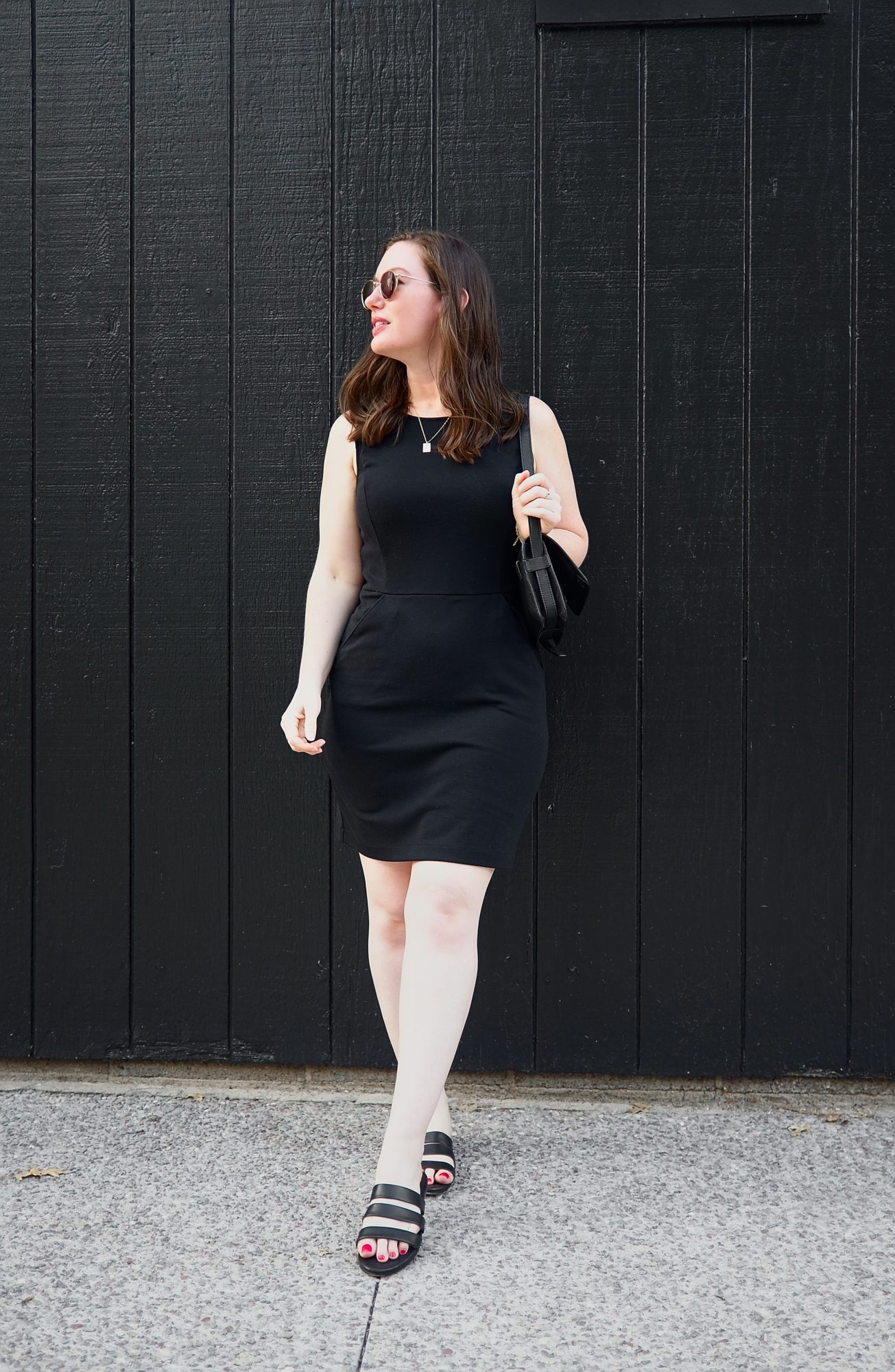 Alyssa wears a black dress in front of a black wall in Rochester, NY