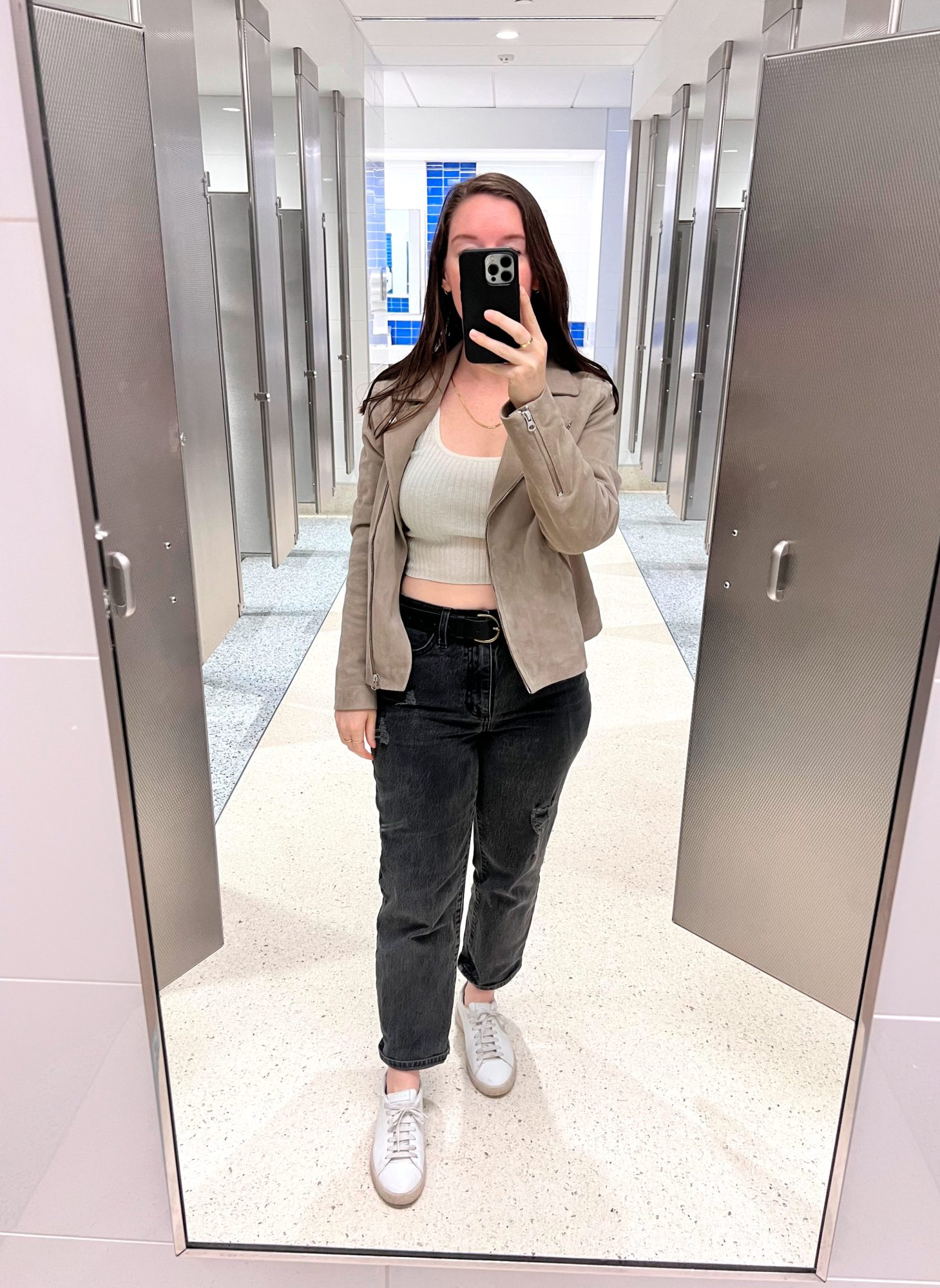 Alyssa wears a crop top and jeans at the airport with a suede jacket