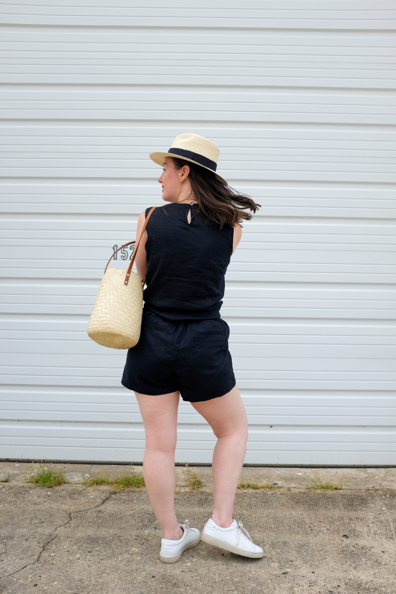 Alyssa wears a black linen top and shorts from Quince and faces away from the camera