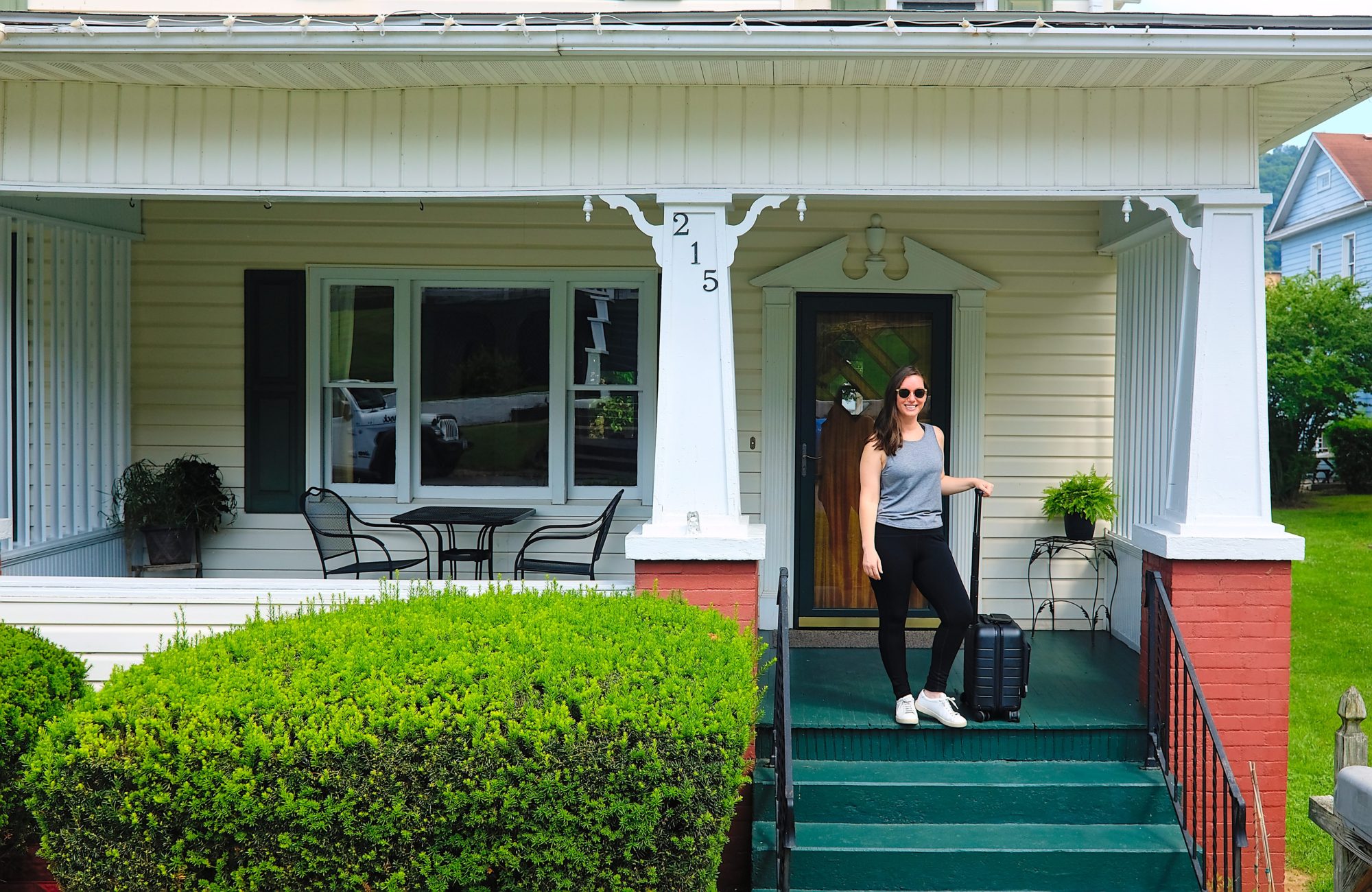 Alyssa stands outside a B&B with a suitcase