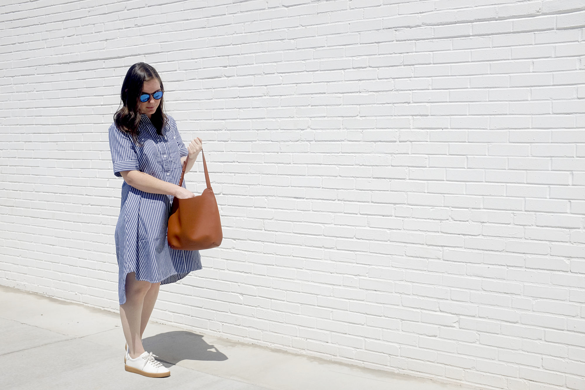 Alyssa wears a blue dress and carries the Everlane Cactus Leather Hobo