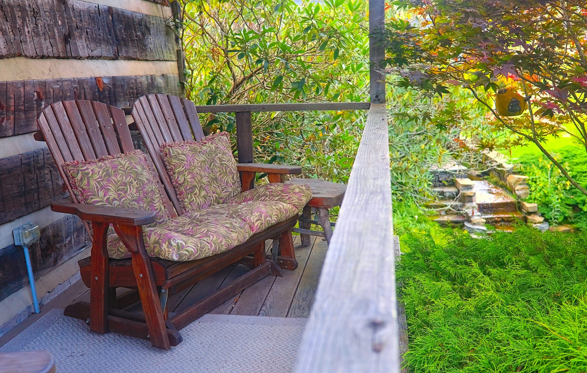 The back porch of the log cabin with a two-person glider chair