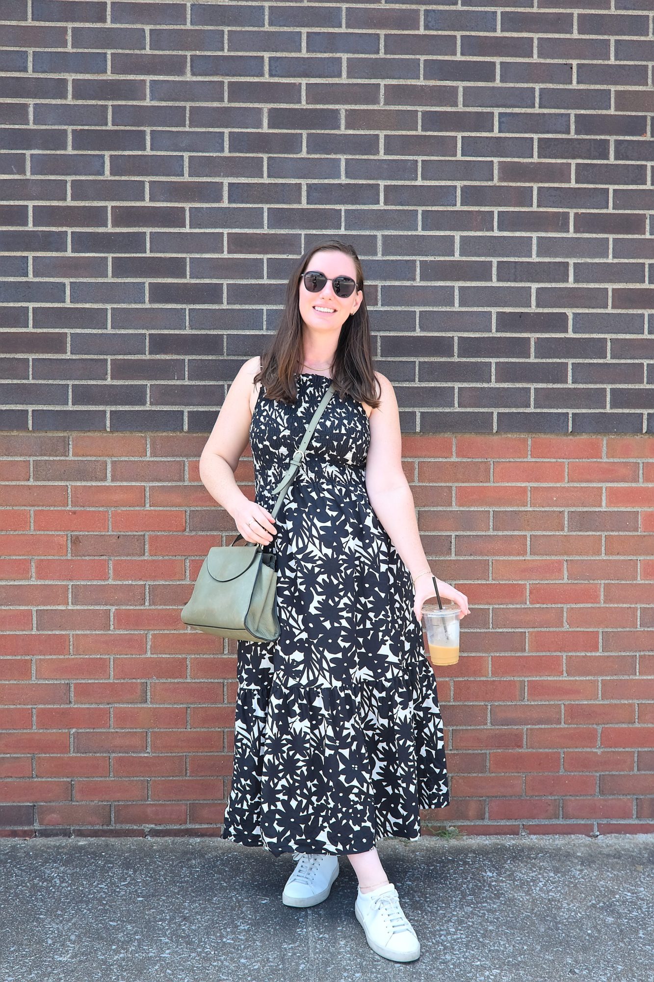 Alyssa stands in front of a brick wall wearing a midi dress and sneakers