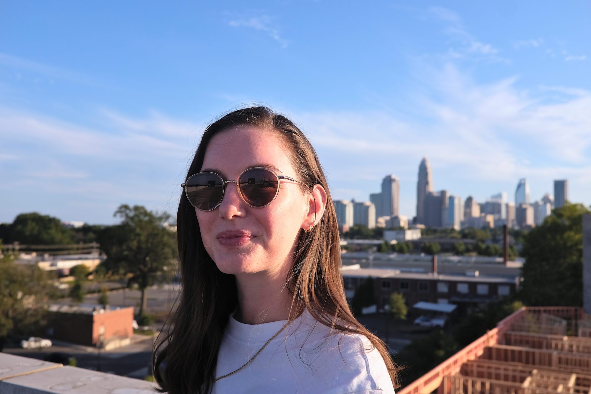 Alyssa wears a pair of Sunski's Baia sunglasses in front of the Charlotte skyline
