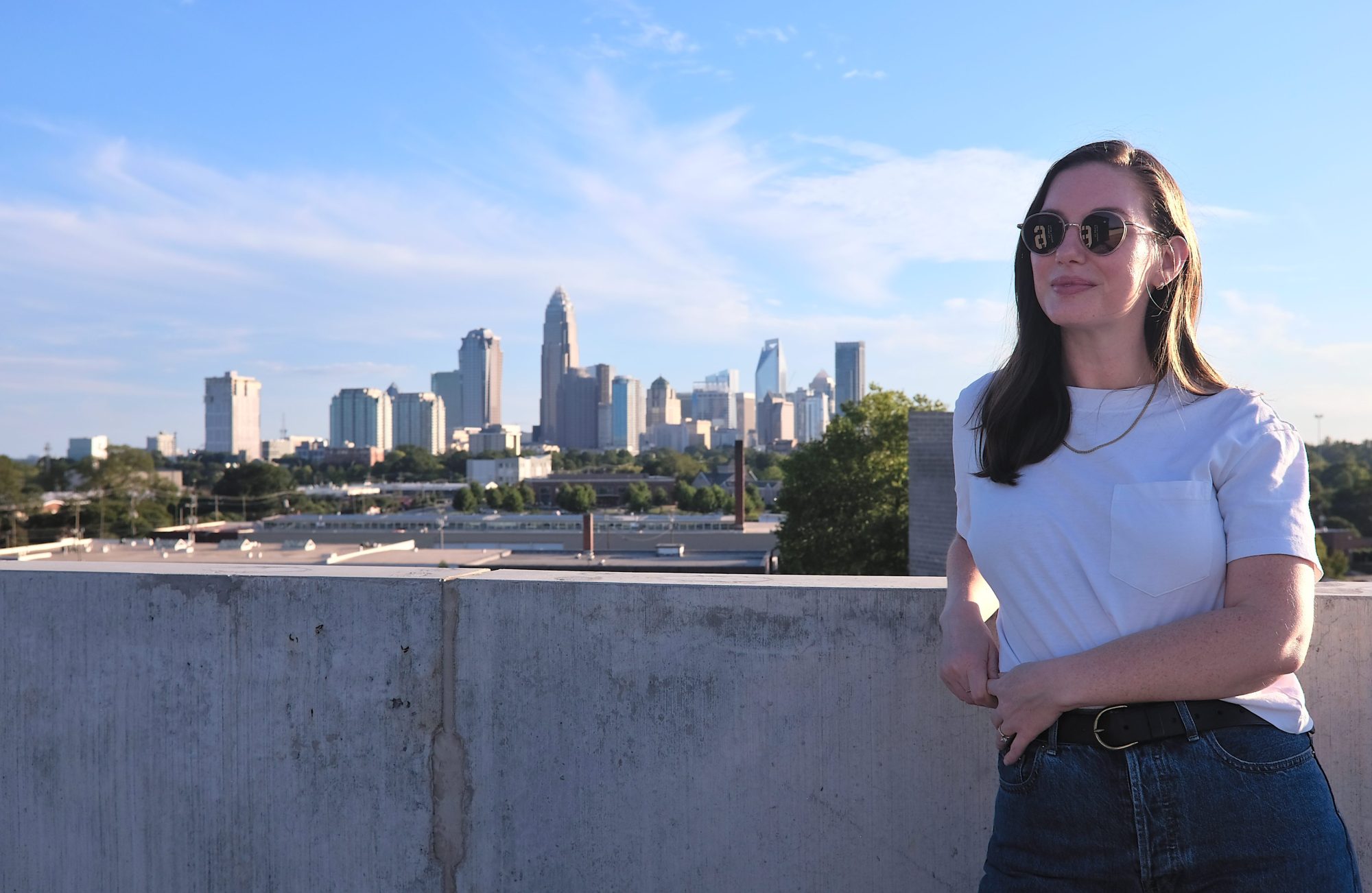 Alyssa wears a pair of Sunski sunglasses with the Charlotte skyline behind her
