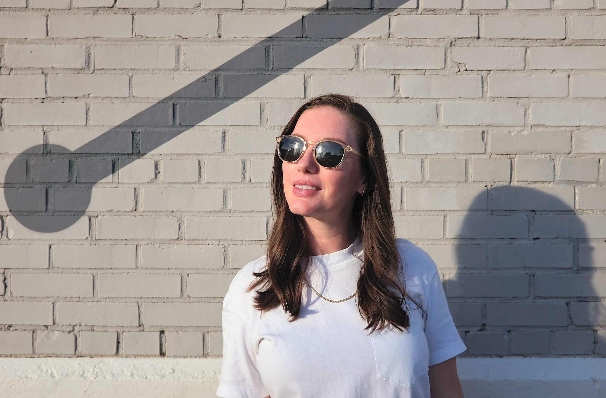 Alyssa wears the Yuba sunglasses in front of a tan brick wall