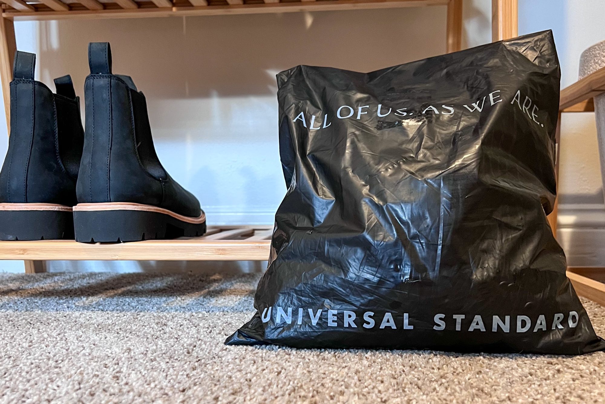A mailer bag from Universal Standard next to a pair of boots