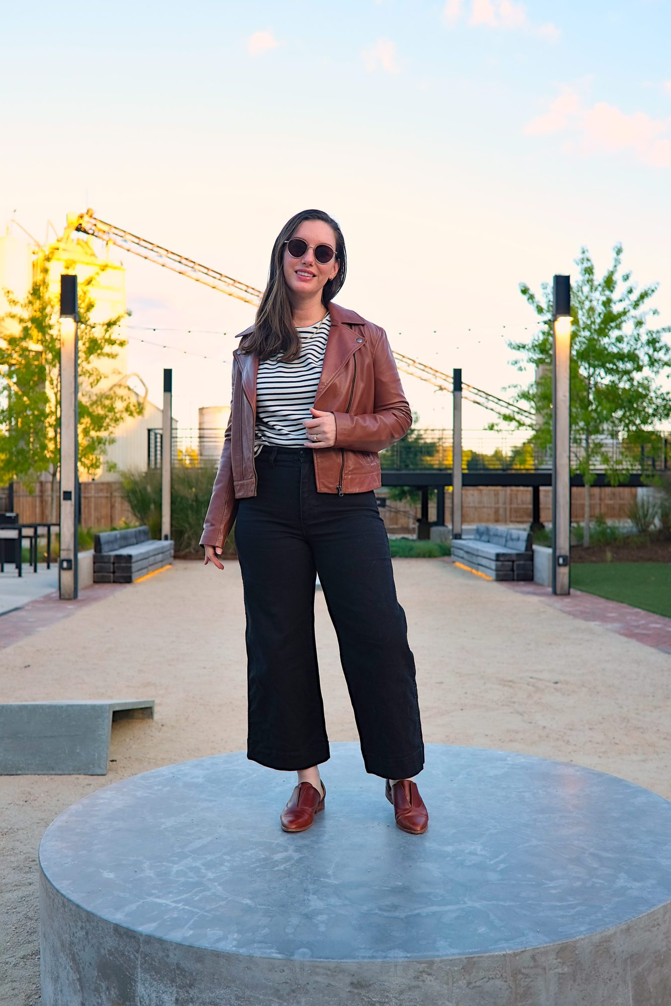 Alyssa wears the ABLE Maha Leather Jacket in an industrial area
