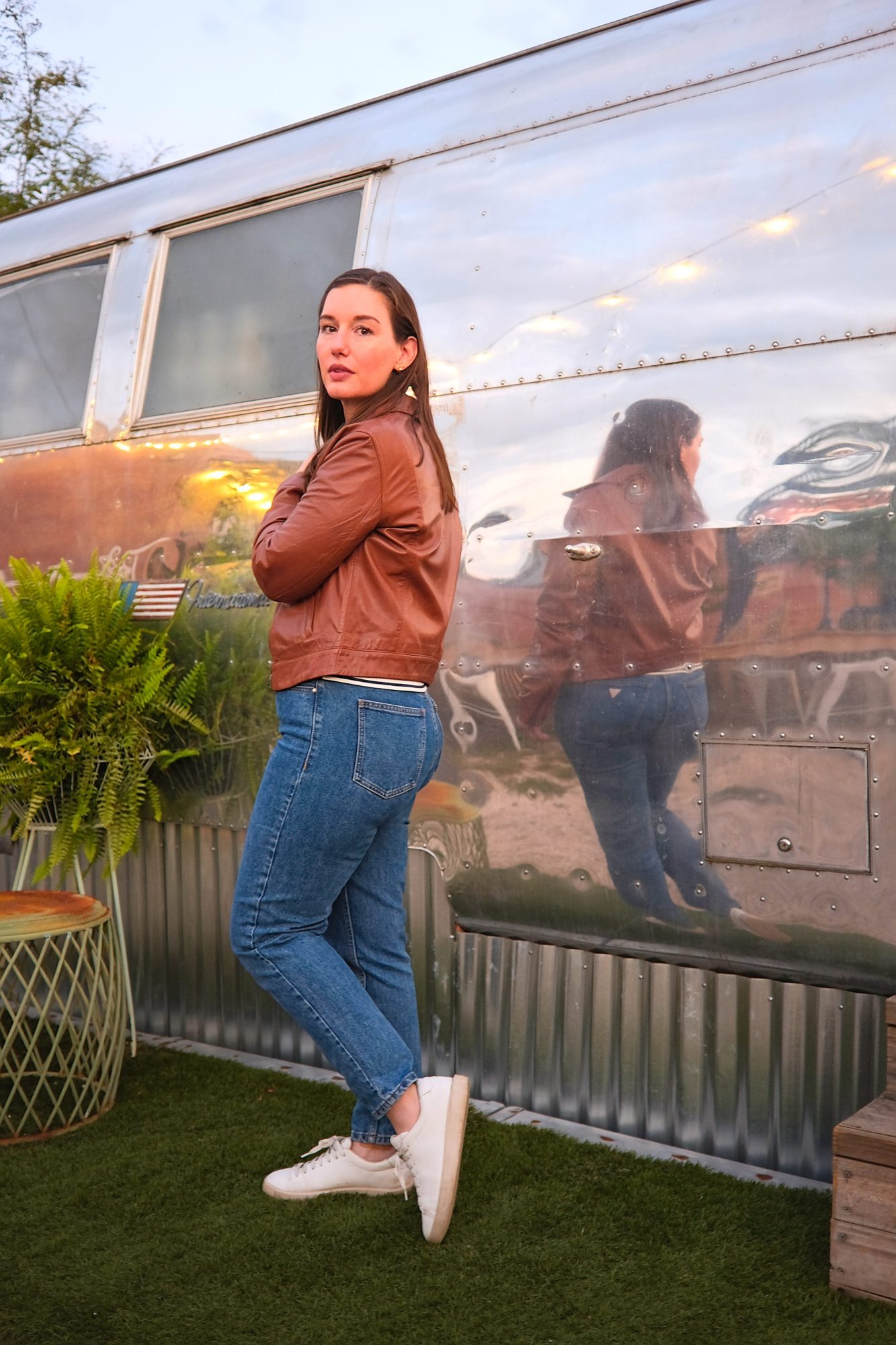 Alyssa wears the Maha Leather Jacket from ABLE in front of an Airstream