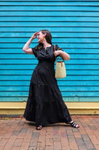 Alyssa wears the Quince Cotton Tiered Maxi Dress with sandals and a basket purse and turns her head to the side