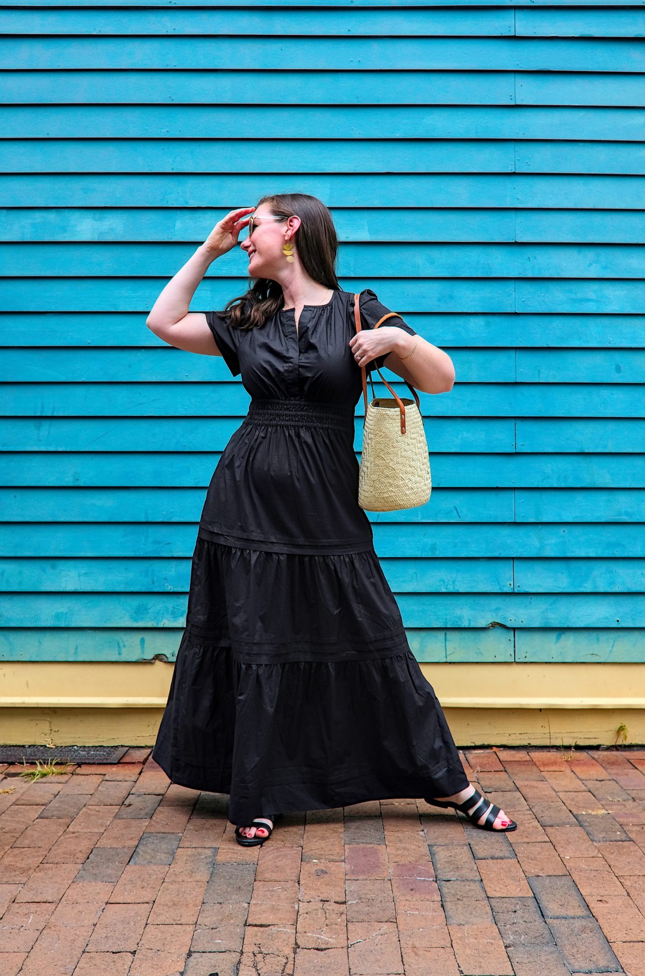Alyssa wears the Quince Cotton Tiered Maxi Dress with sandals and a basket purse and turns her head to the side