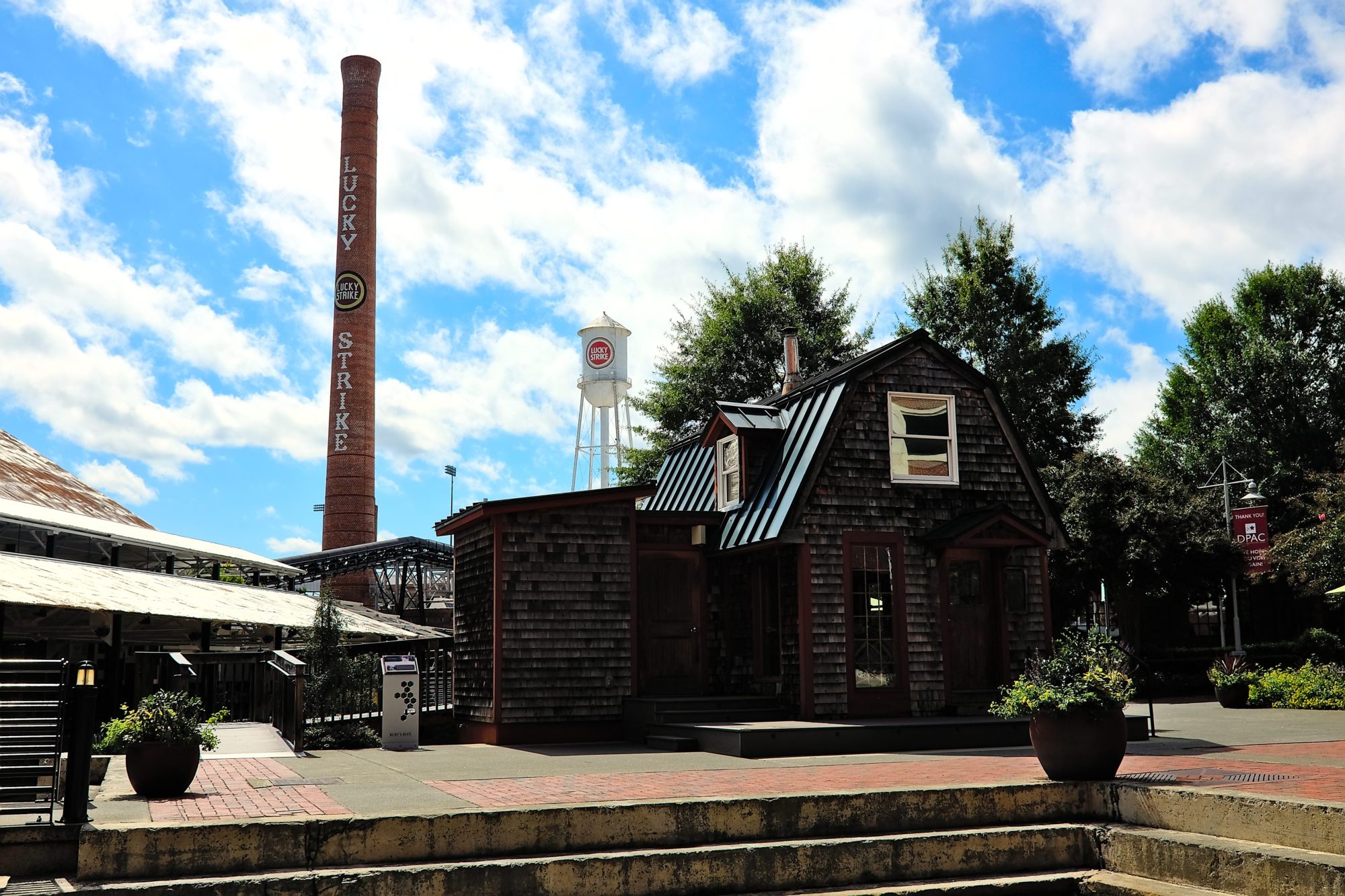 The Burt Shavitz cabin is in the foreground, with the Lucky Strike water tower and smoke stack in the background