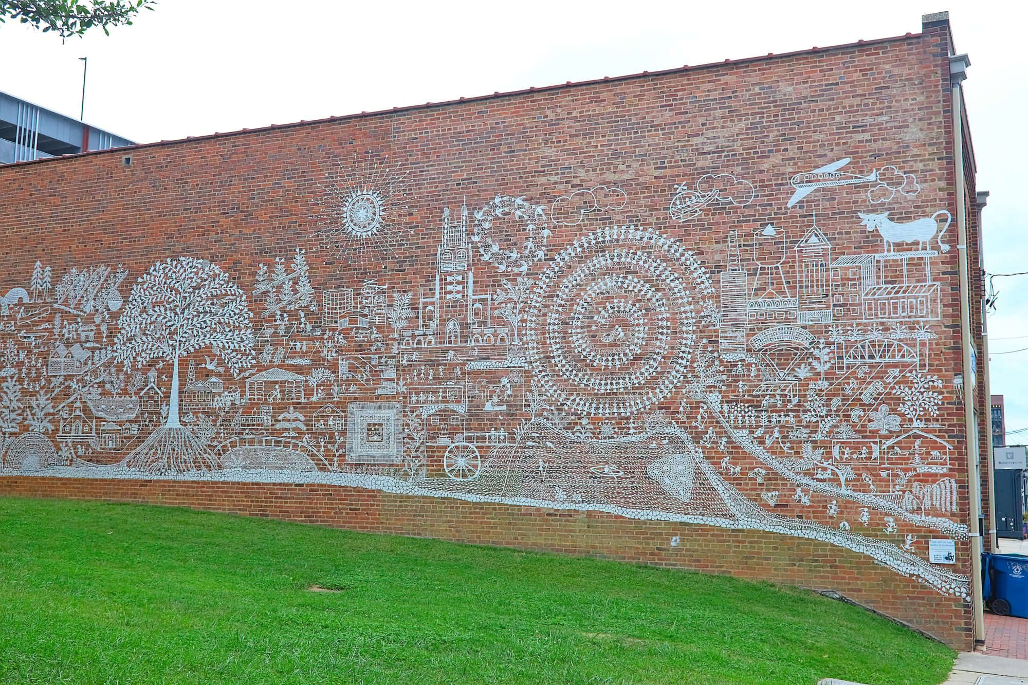 A white mural of Durham on a red brick wall