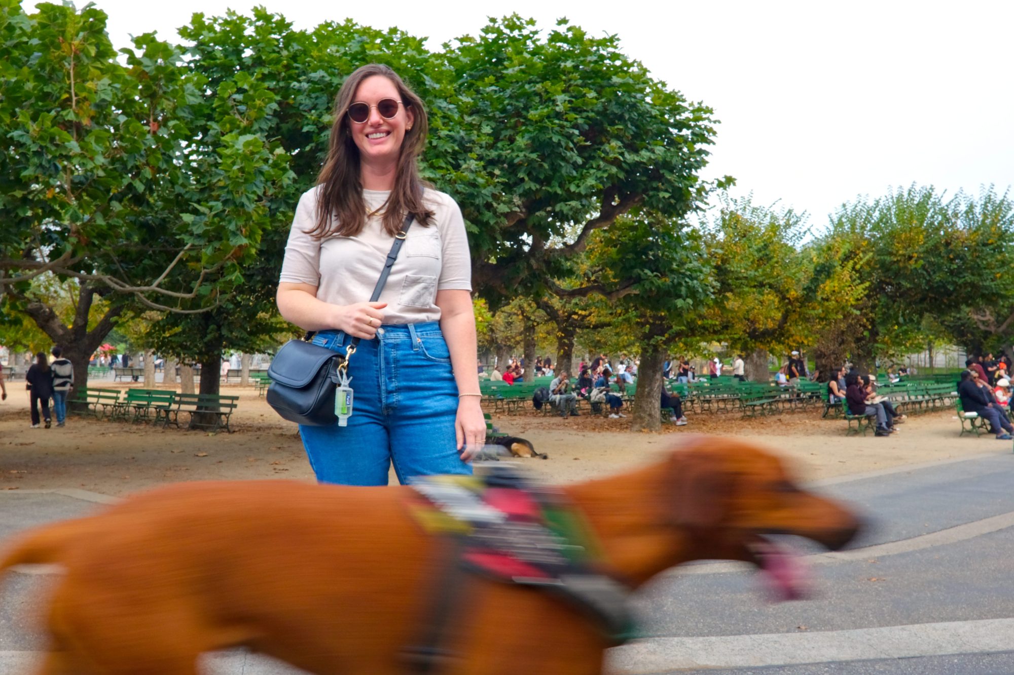 Alyssa smiles for a photo and a dog runs past