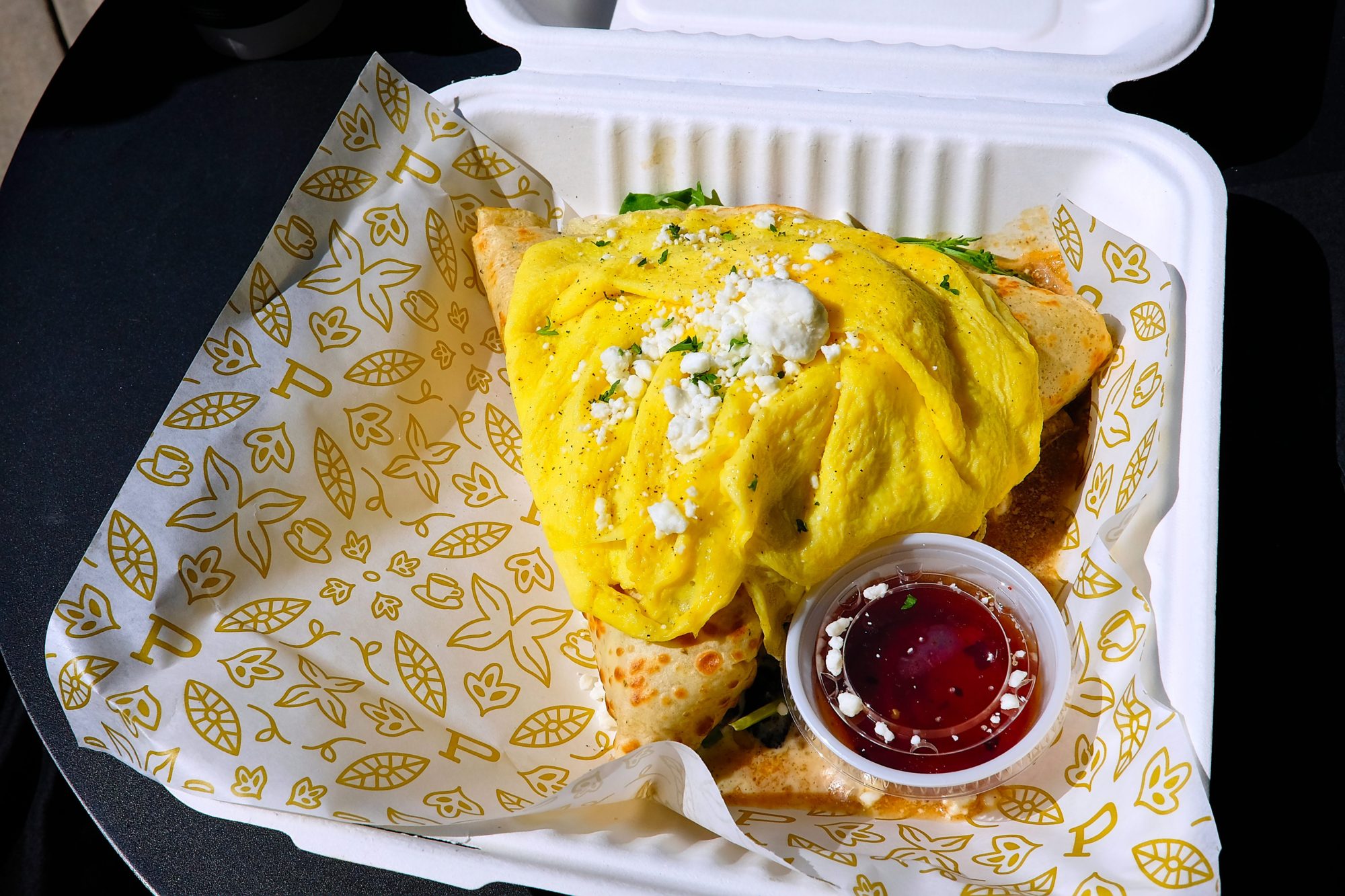 A crepe in a takeout box with an egg on top