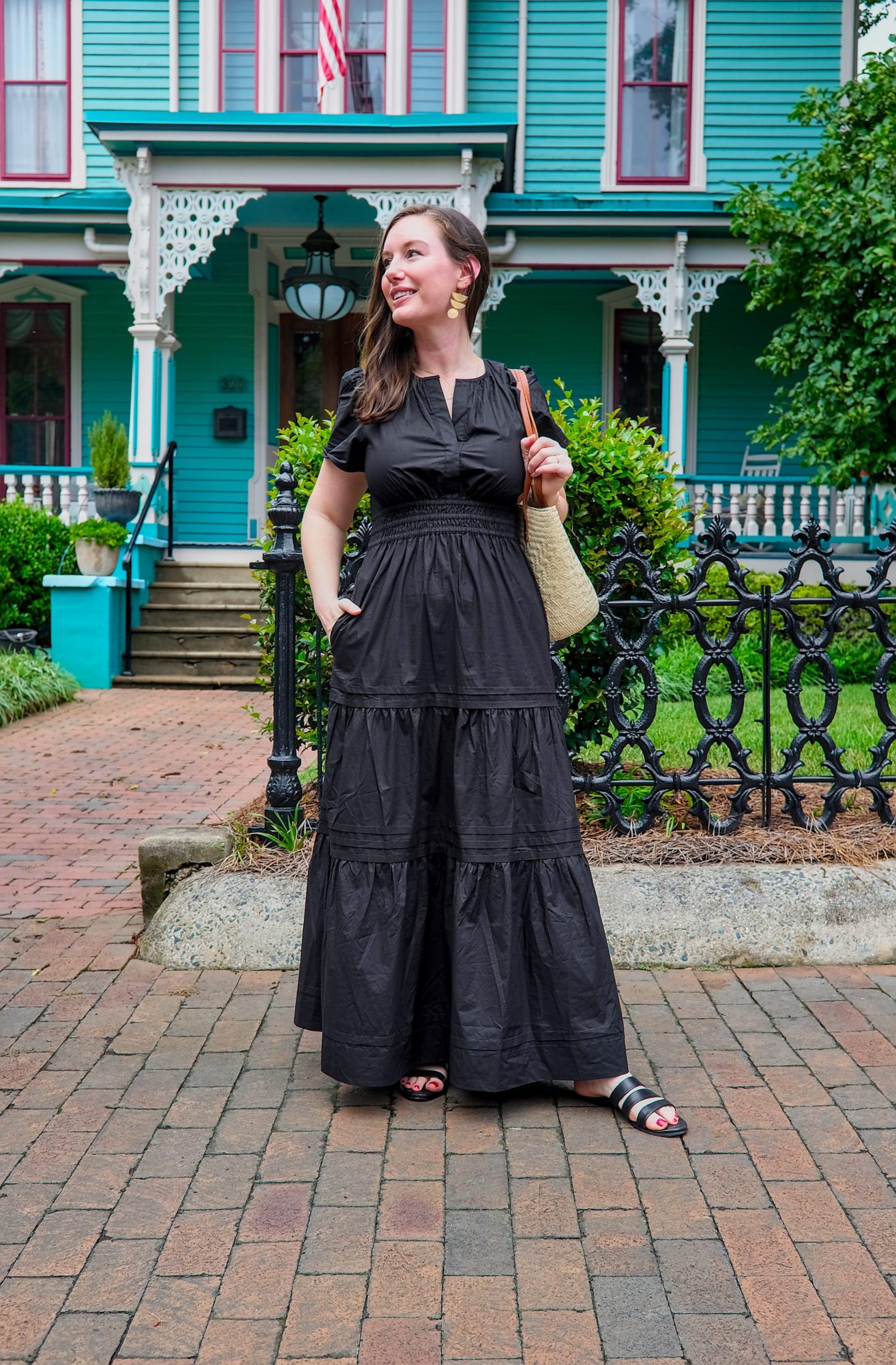 Alyssa wears the Quince Cotton Poplin Maxi Dress in black and stands in front of a Victorian home