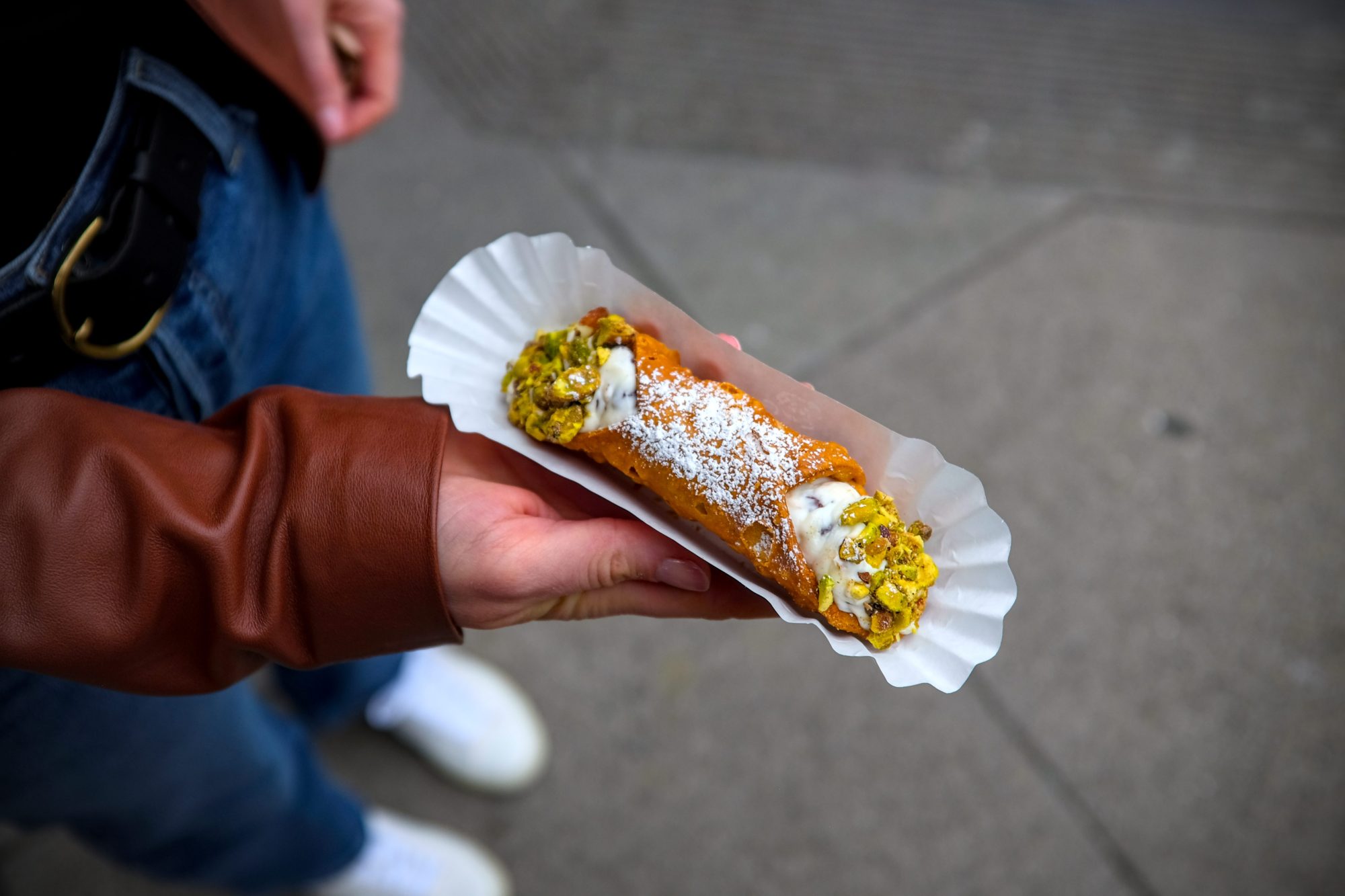 Alyssa holds a cannoli on a sidewalk in San Francisco