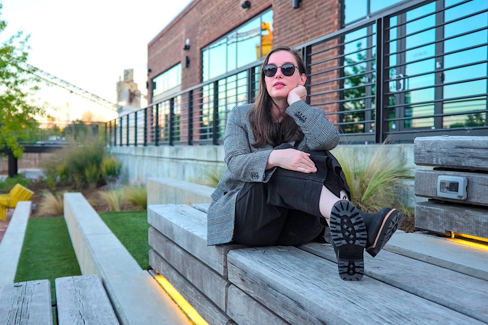 Alyssa sits and rests her chin in her hand while wearing the Nisolo boots