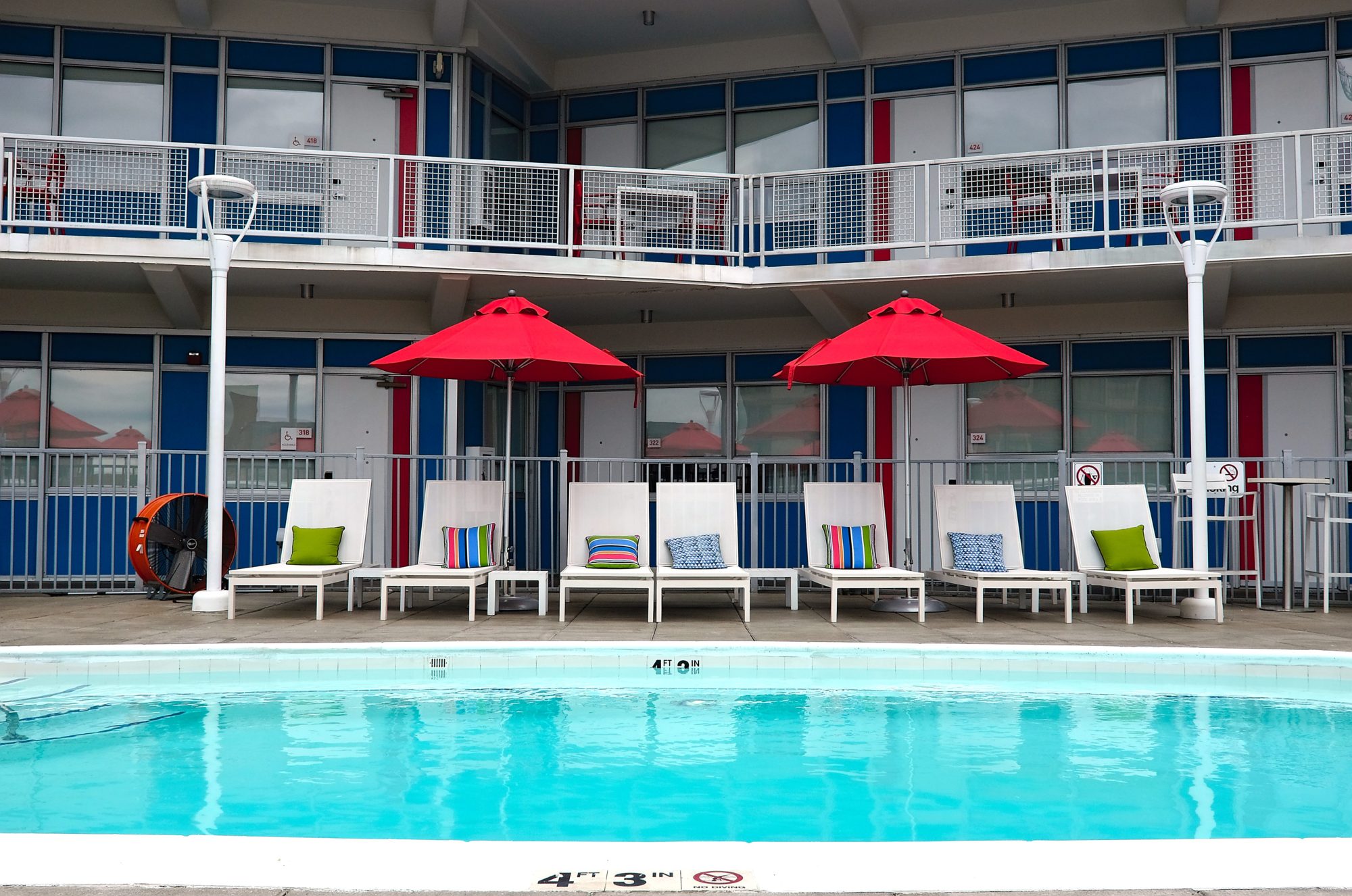 A row of chairs by the pool at Unscripted Durham, with the hotel rooms in the background