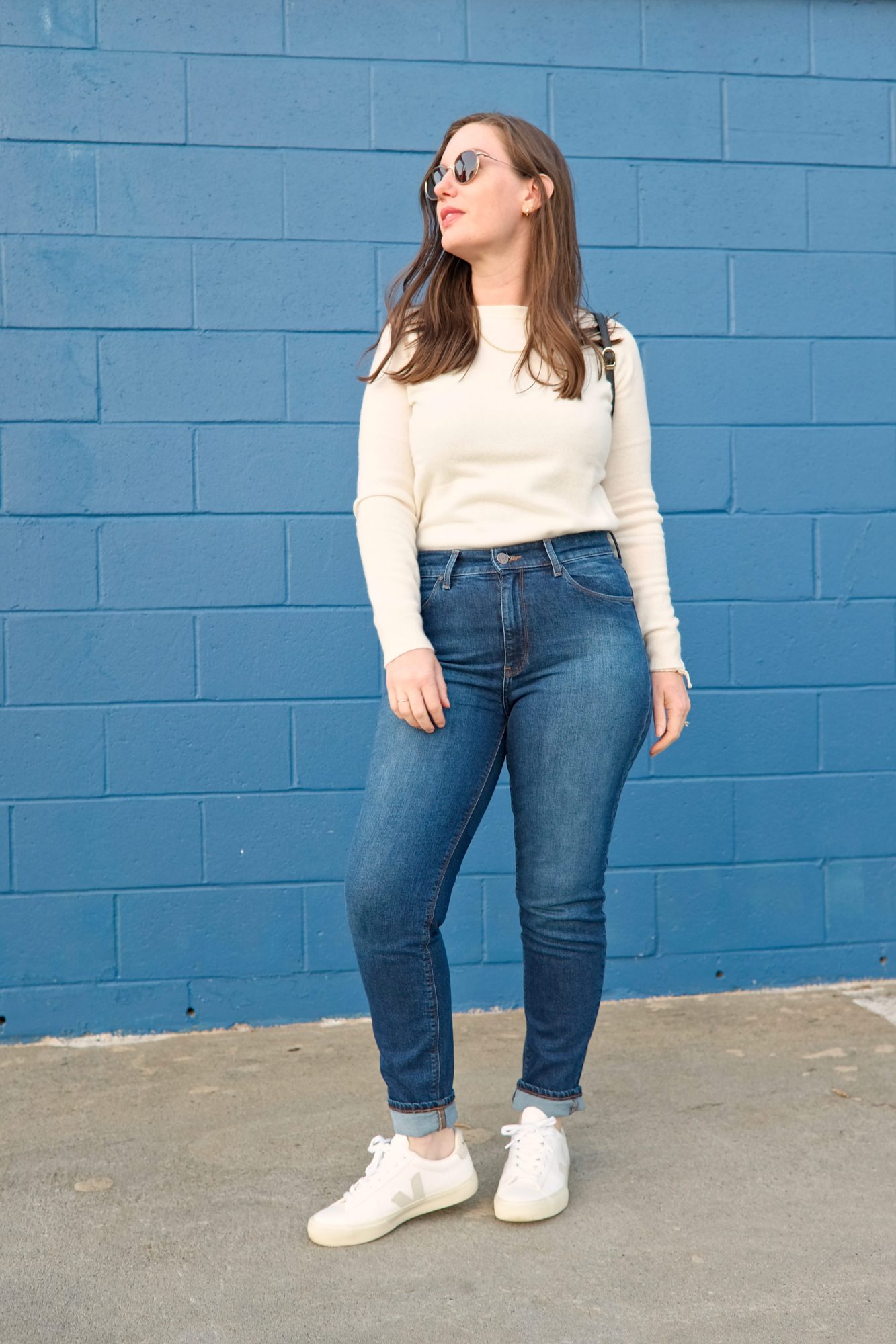 Alyssa wears a white sweater with blue jeans and white sneakers