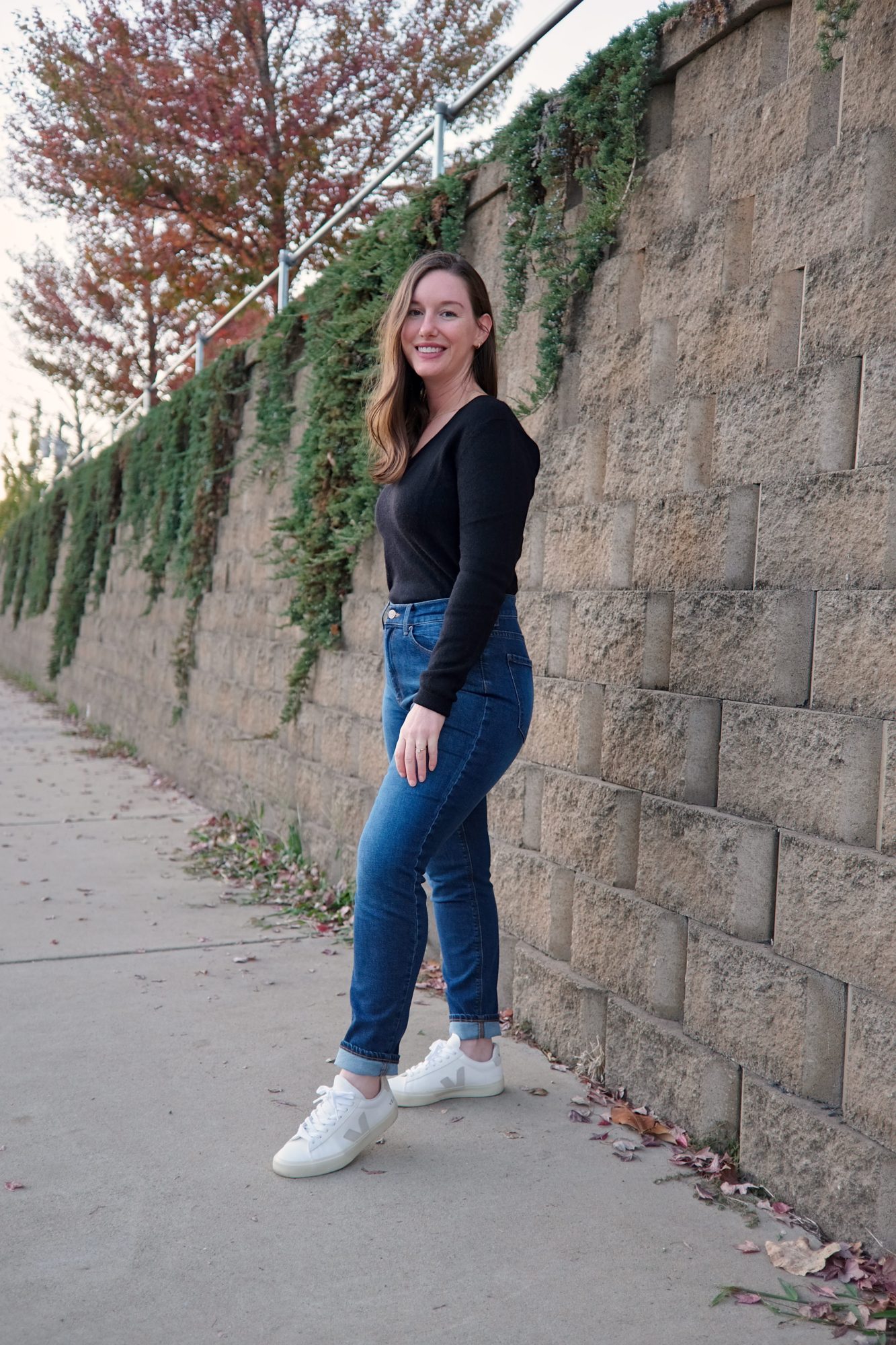Alyssa wears a black cashmere sweater with blue jeans and white sneakers