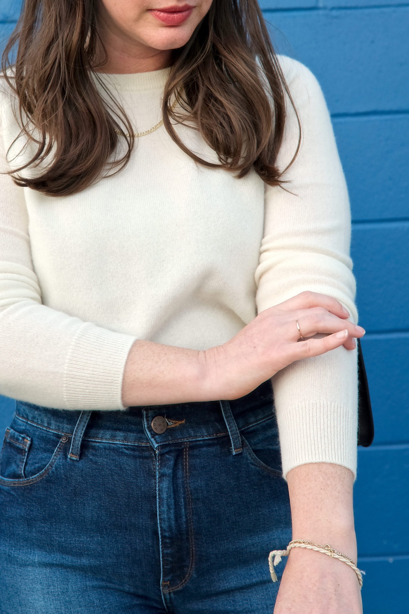 Alyssa pulls up the sleeve of a cream sweater from Mott & Bow