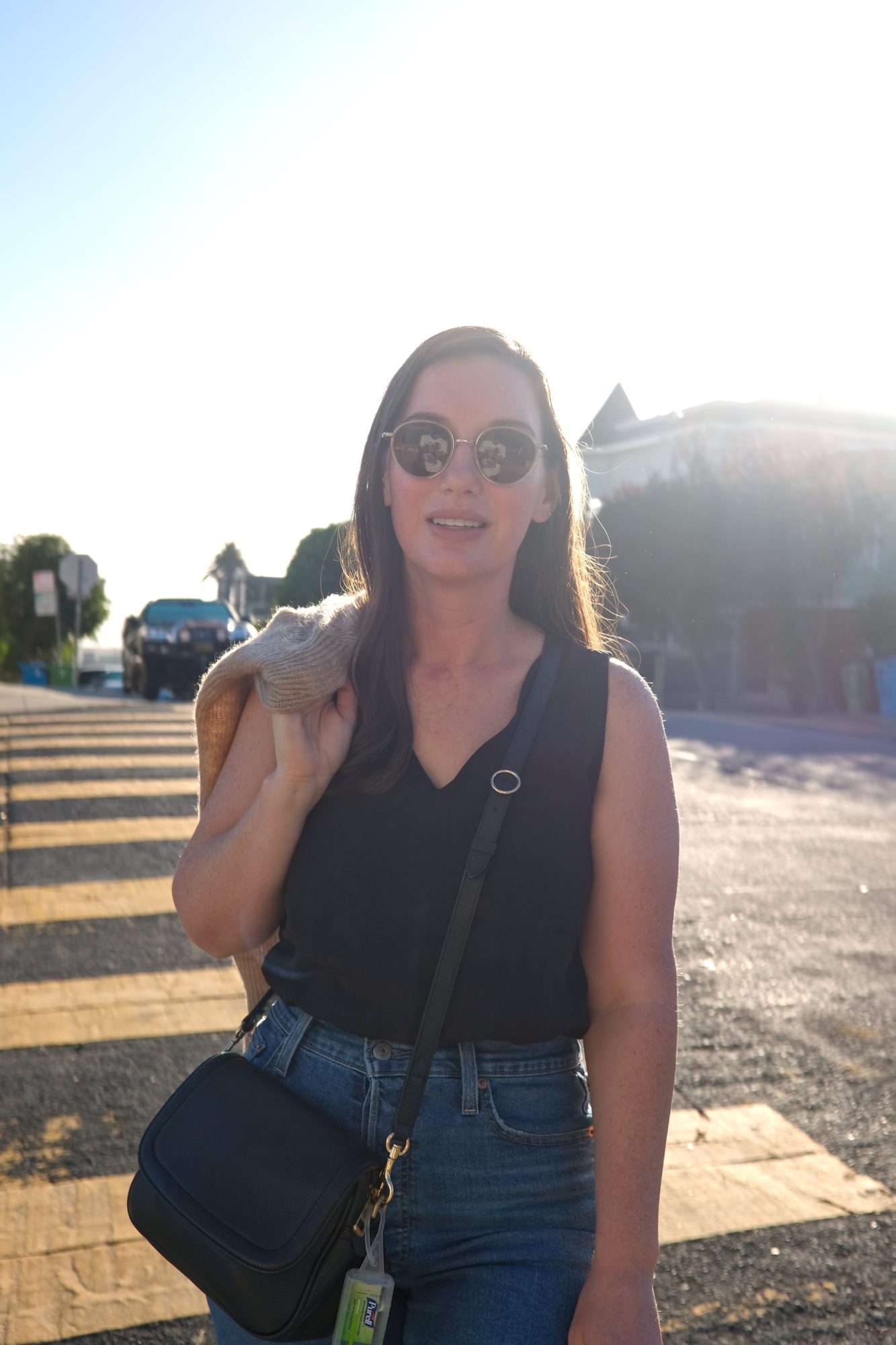 Alyssa wears a black tank with jeans and carries a cardigan