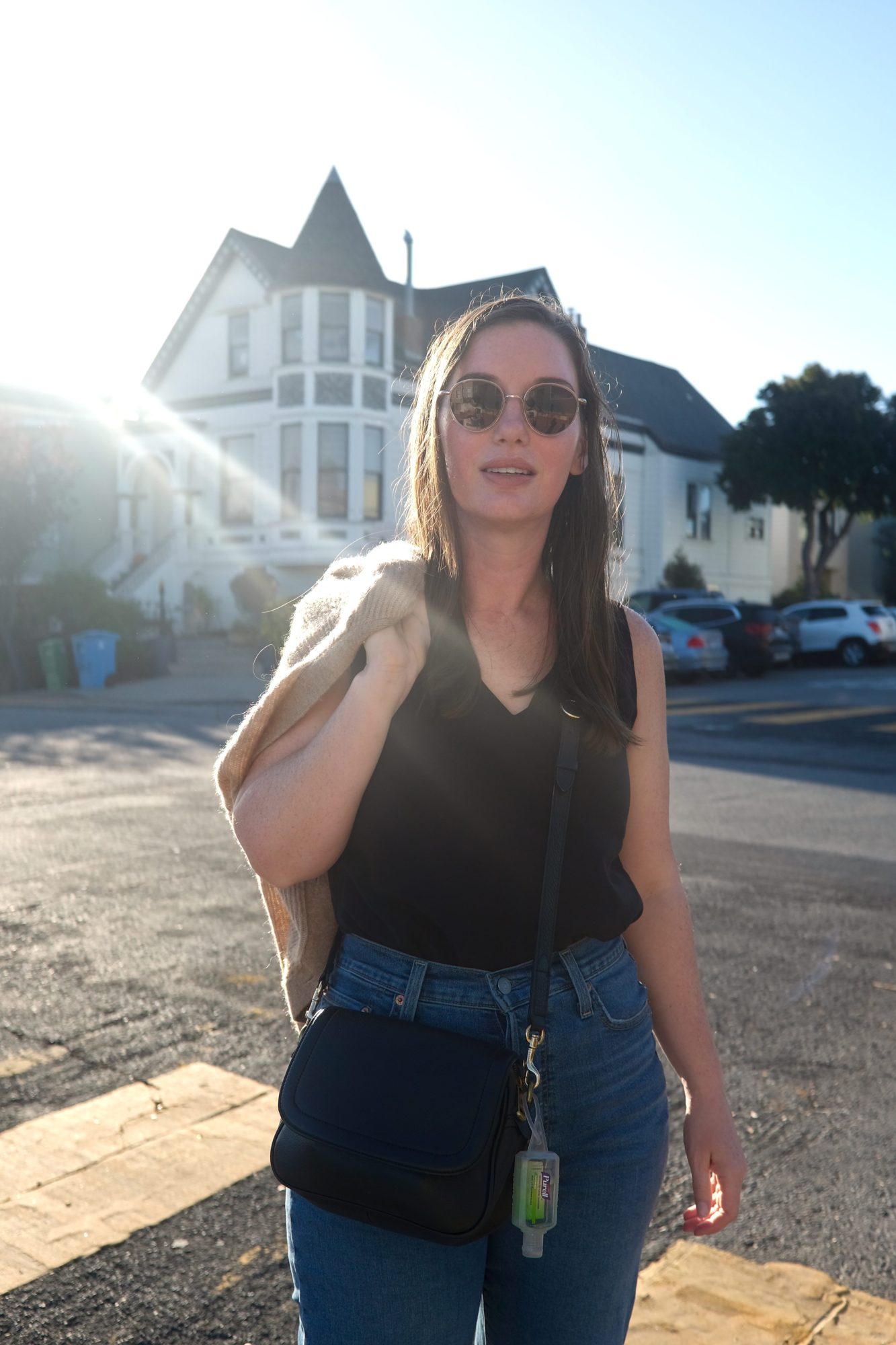 Alyssa holds a cardigan and wears a black tank and jeans in San Francisco