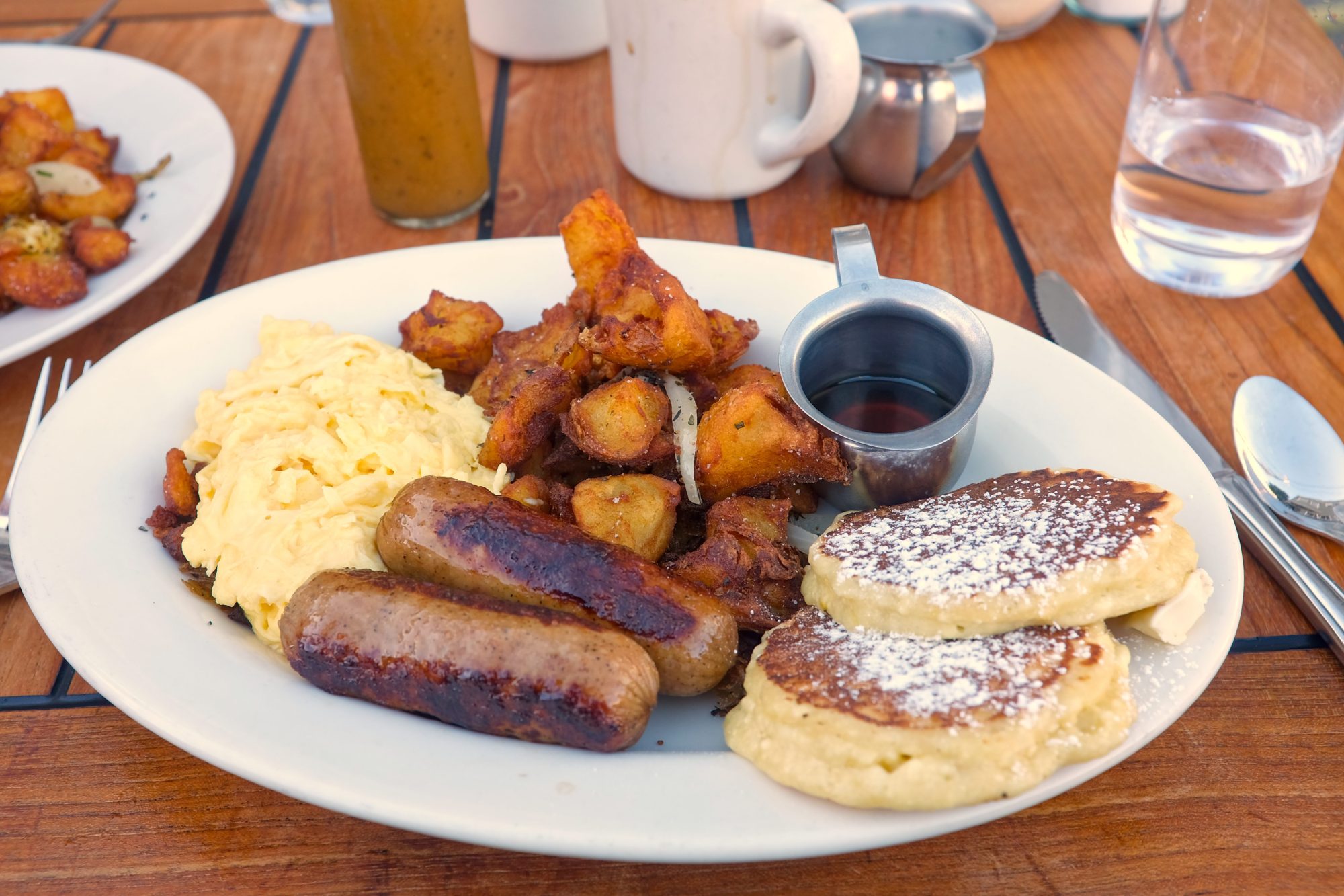 A plate of pancakes, eggs, sausage, and potatoes at Plow
