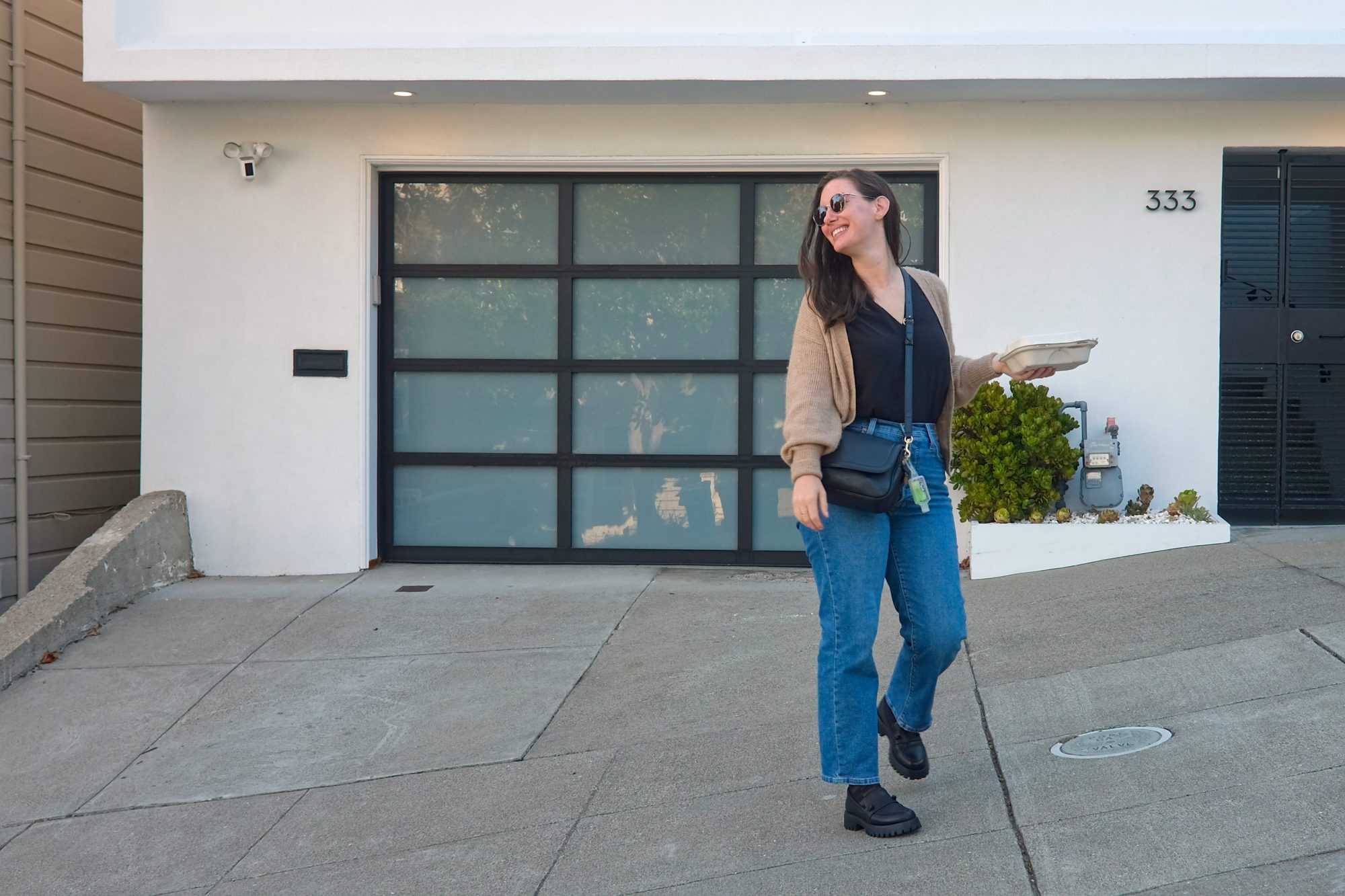 Alyssa walks down a street in San Francisco wearing a black tank with jeans and a cardigan