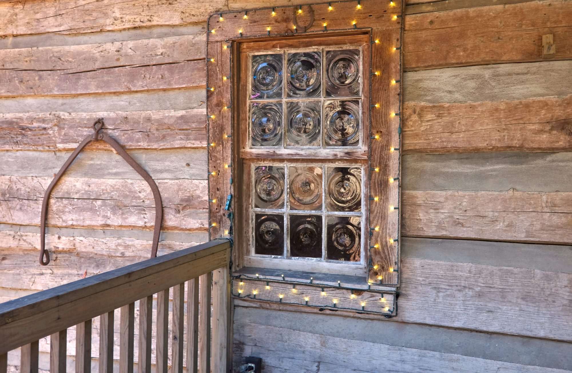 A rustic window rimmed with Christmas lights