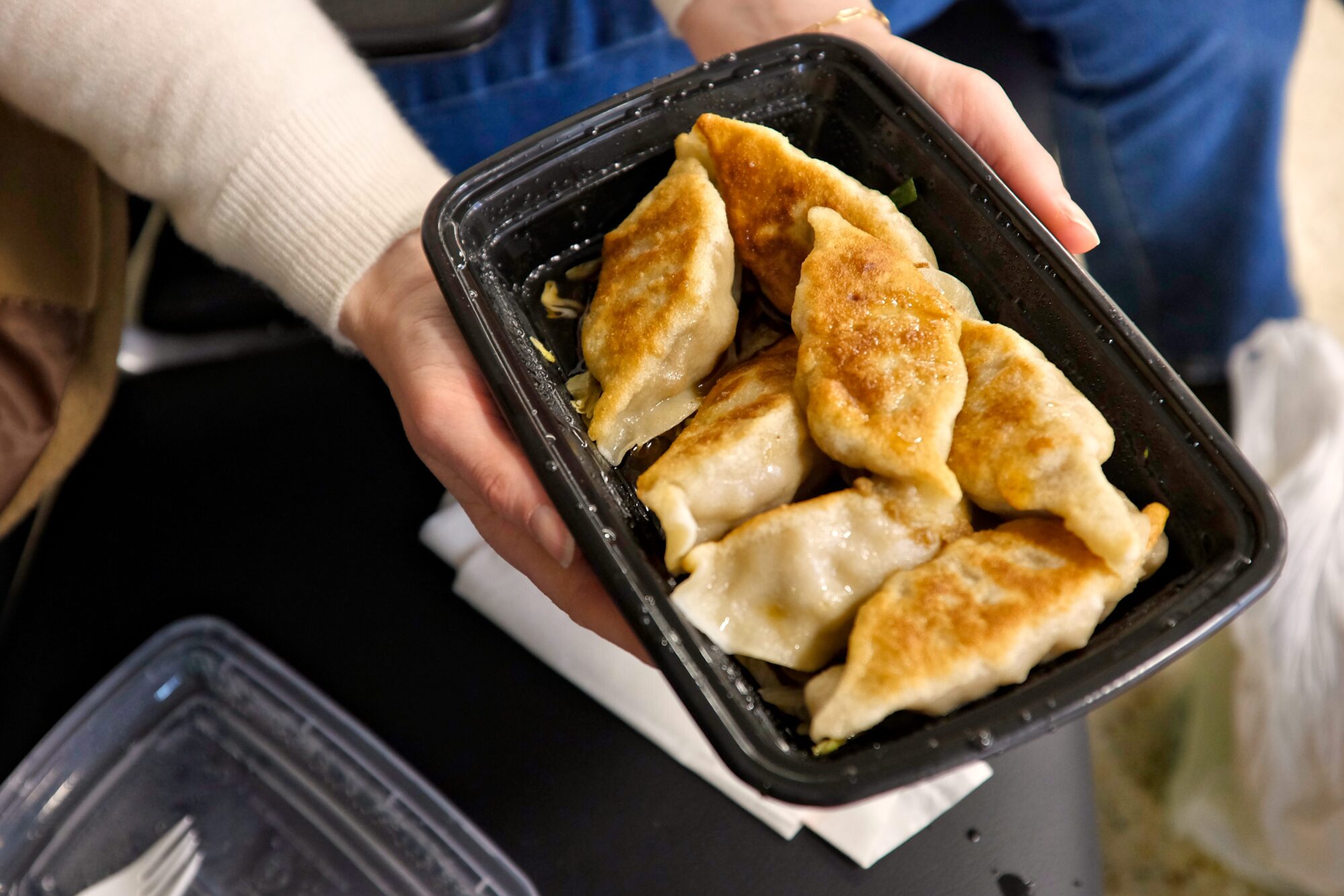 Alyssa holds a takeout box of dumplings