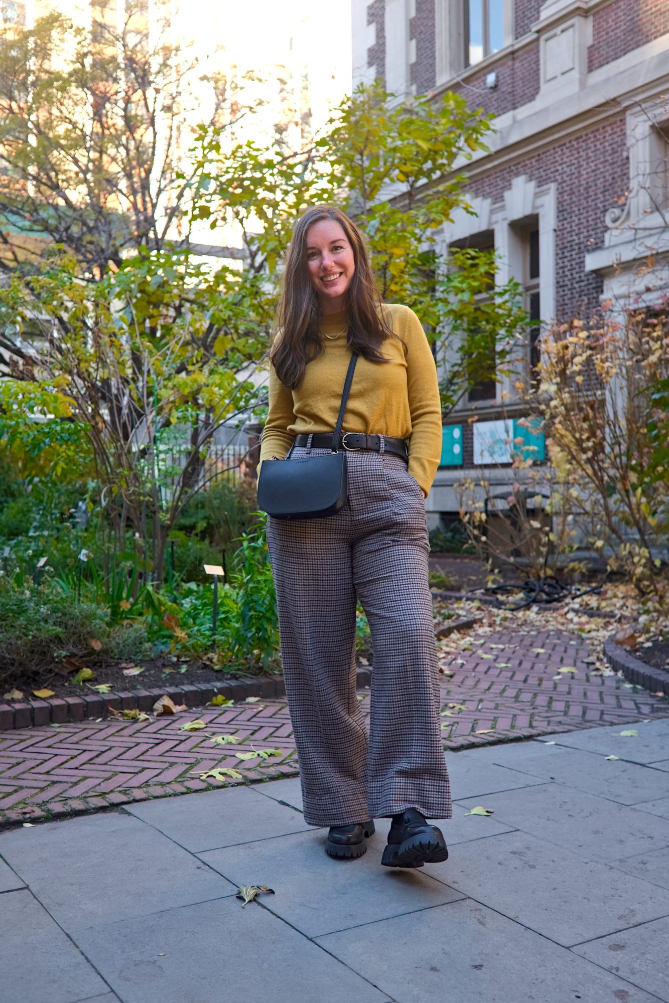 Alyssa wears a mustard sweater and wool trousers in Philadelphia