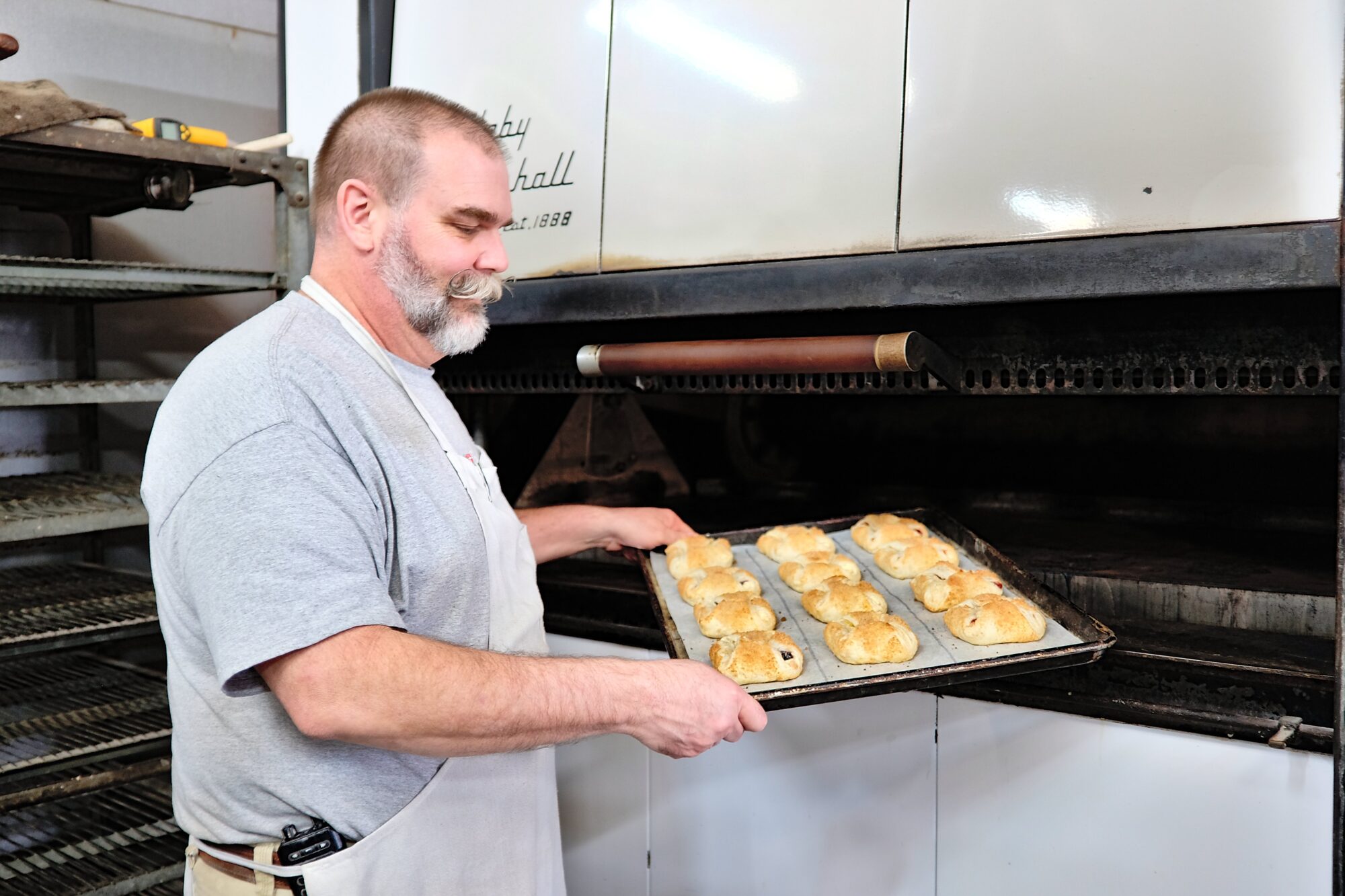 Shawn Oke, owner of Albemarle Sweet Shop, pulls a tray of baked goods from the oven