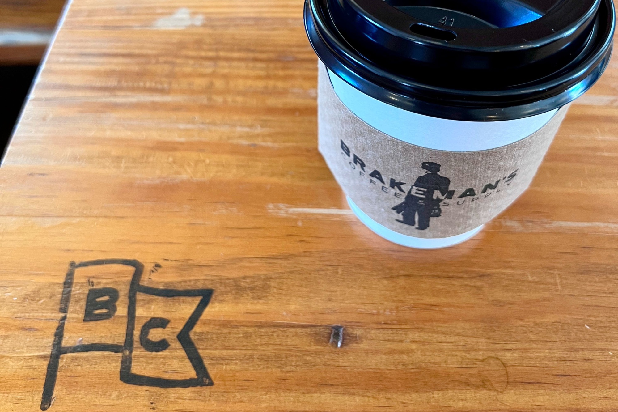 A coffee cup on a table with a logo for Brakemans.
