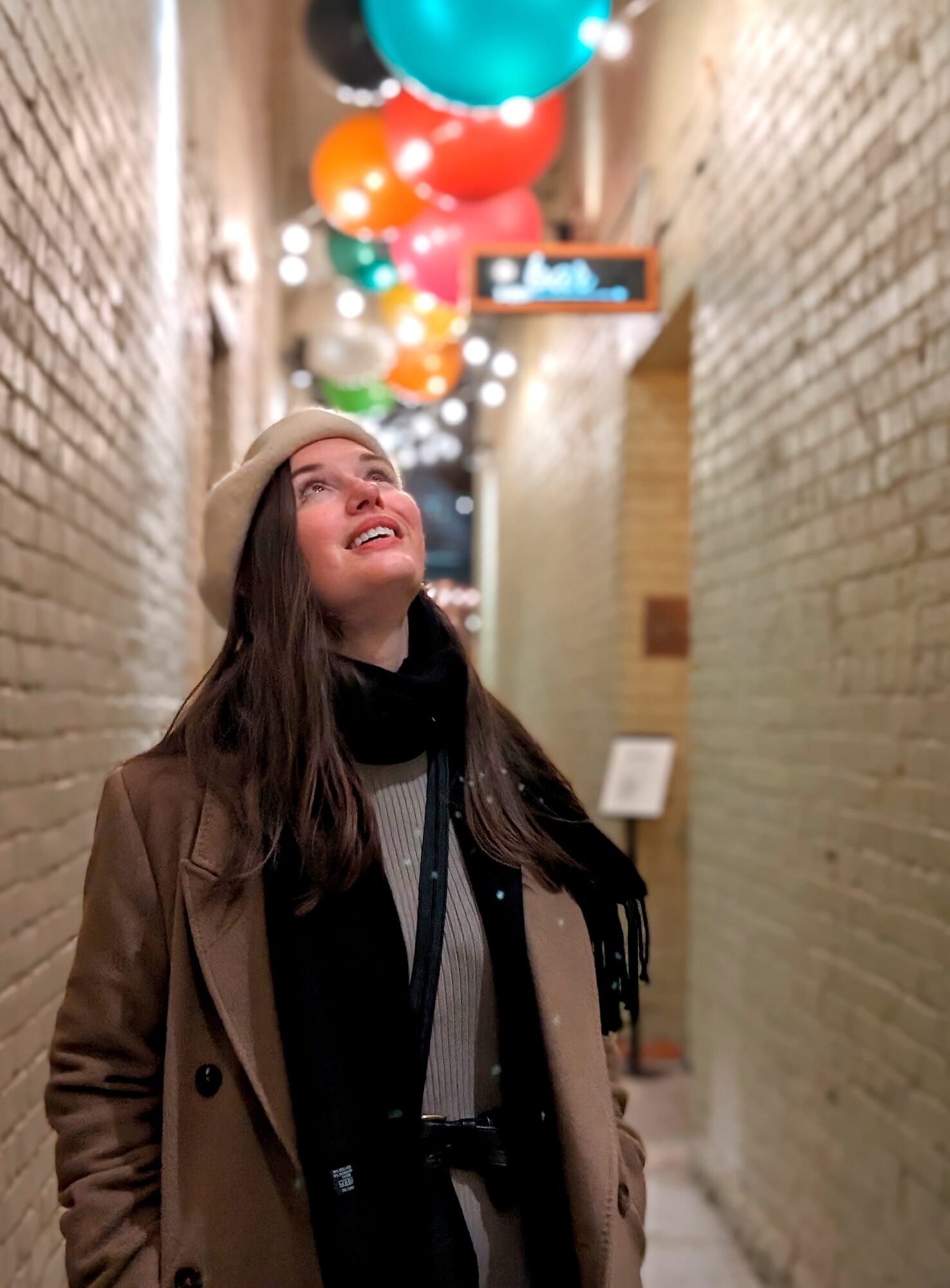 Alyssa looks up at bright balloons in an alley at night