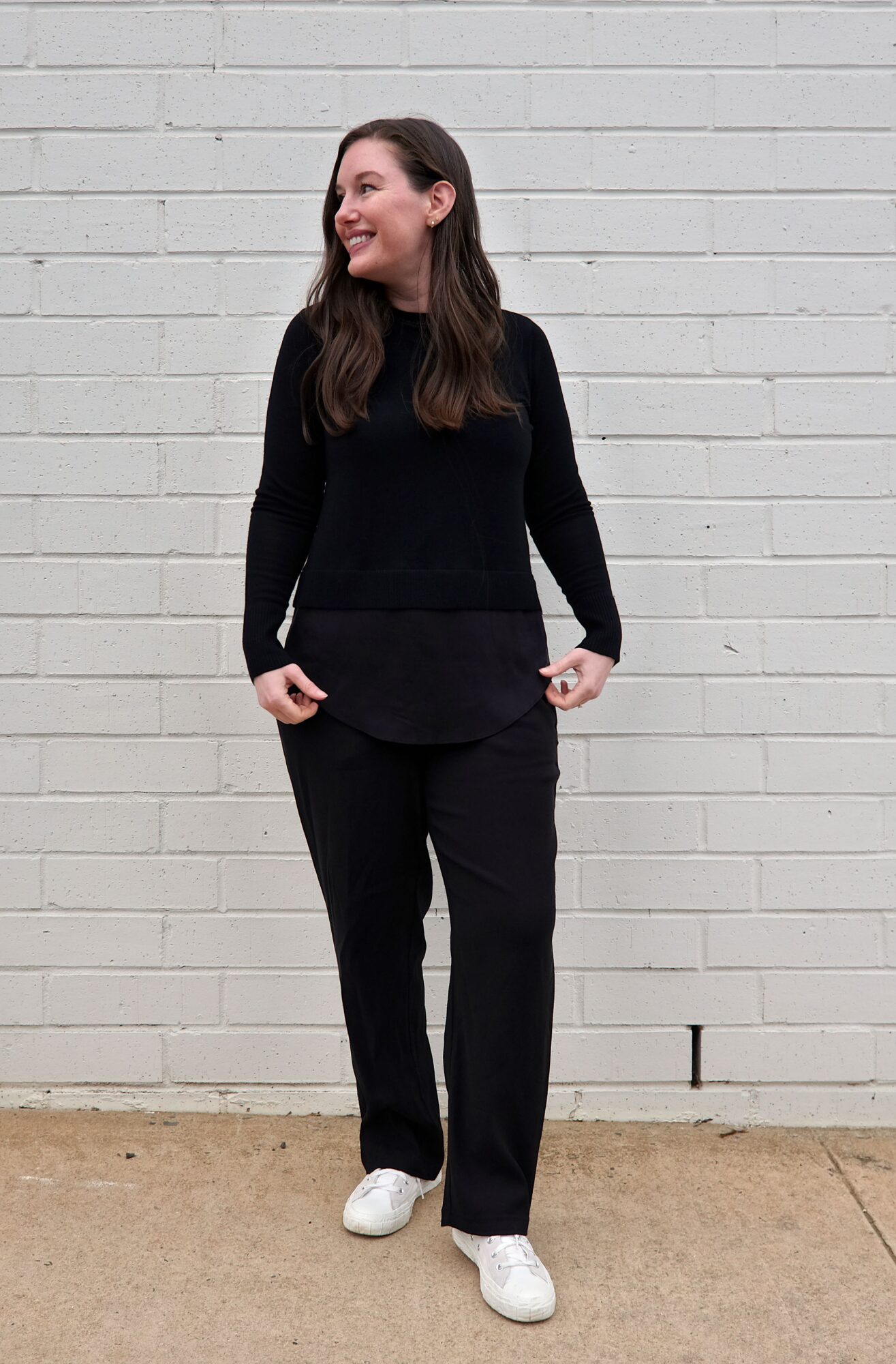 Alyssa wears a black sweater with a mock-shirttail hanging out