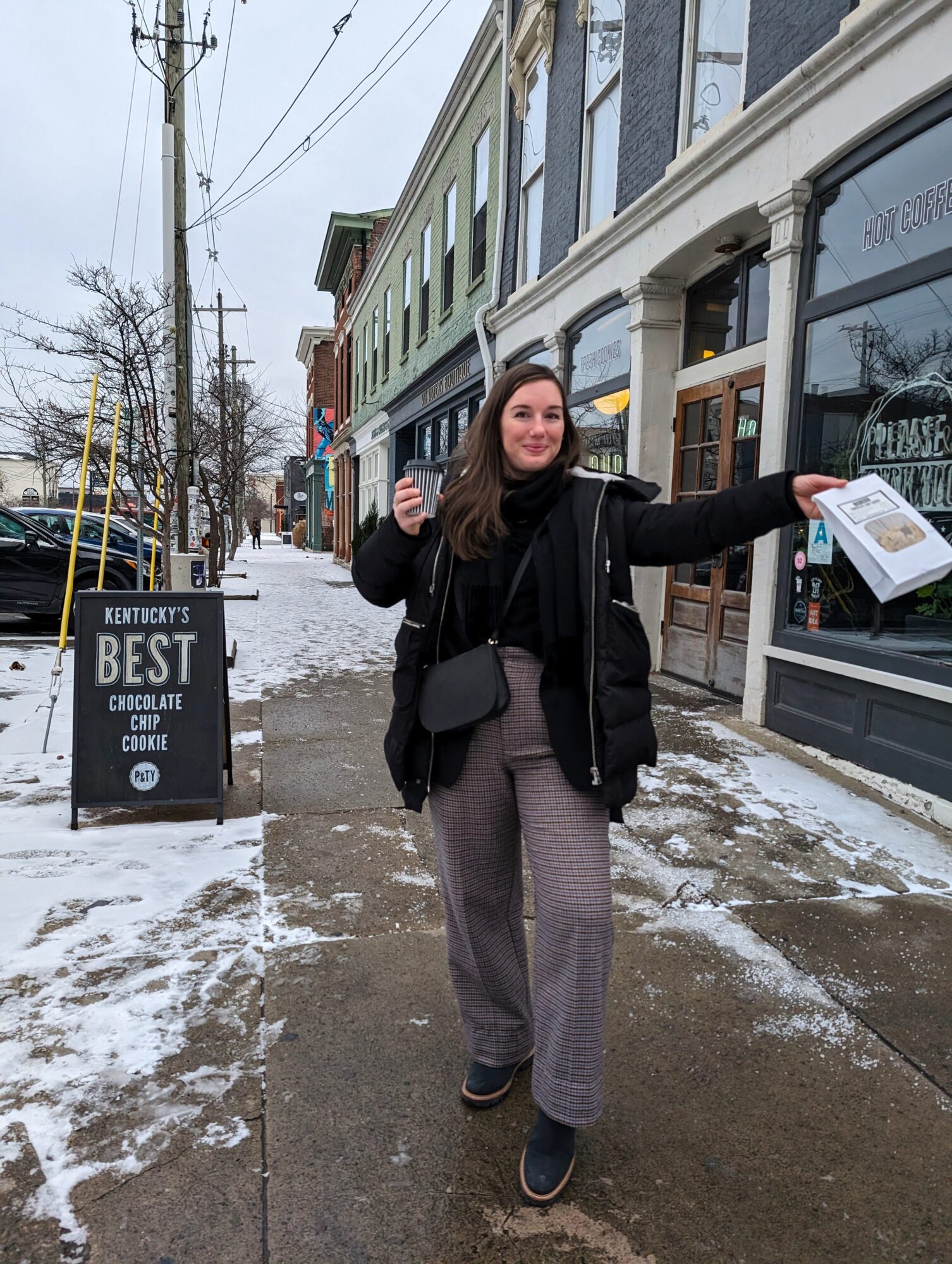 Alyssa wears a black turtleneck with grey wool pants and a puffer coat