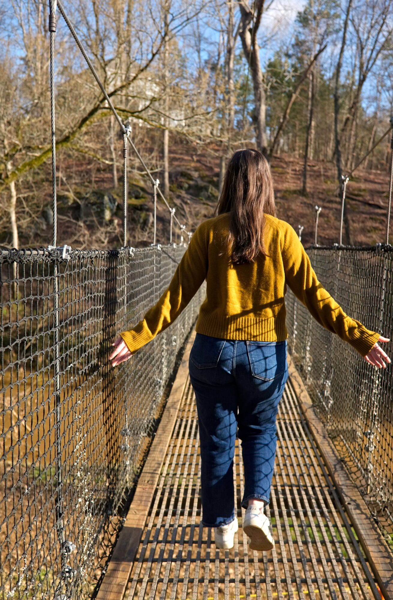 Alyssa walks on the Carolina Thread Trail Suspension Bridge and runs her fingers over the sides
