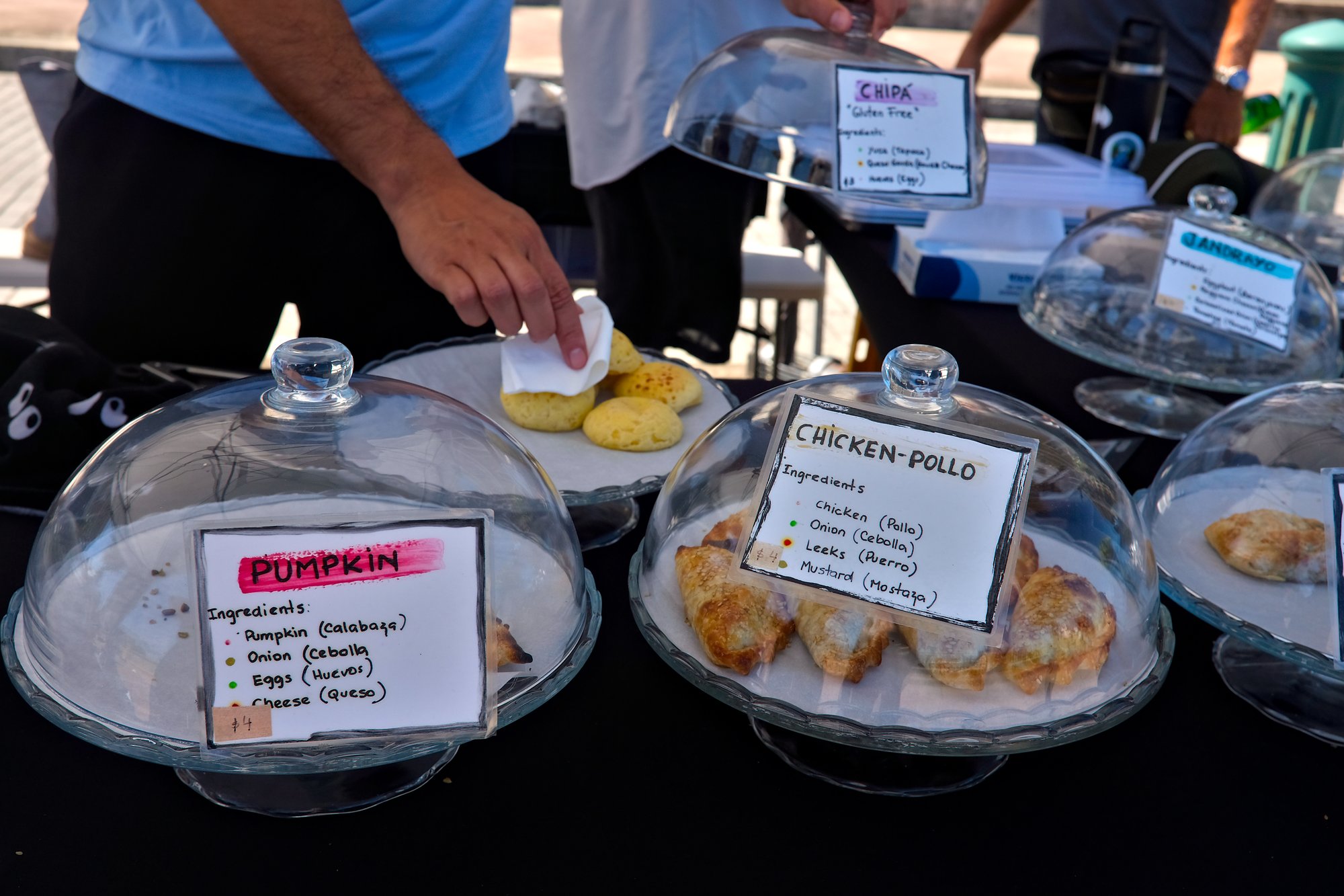 A hand grabs a cheese bread from a glass dome